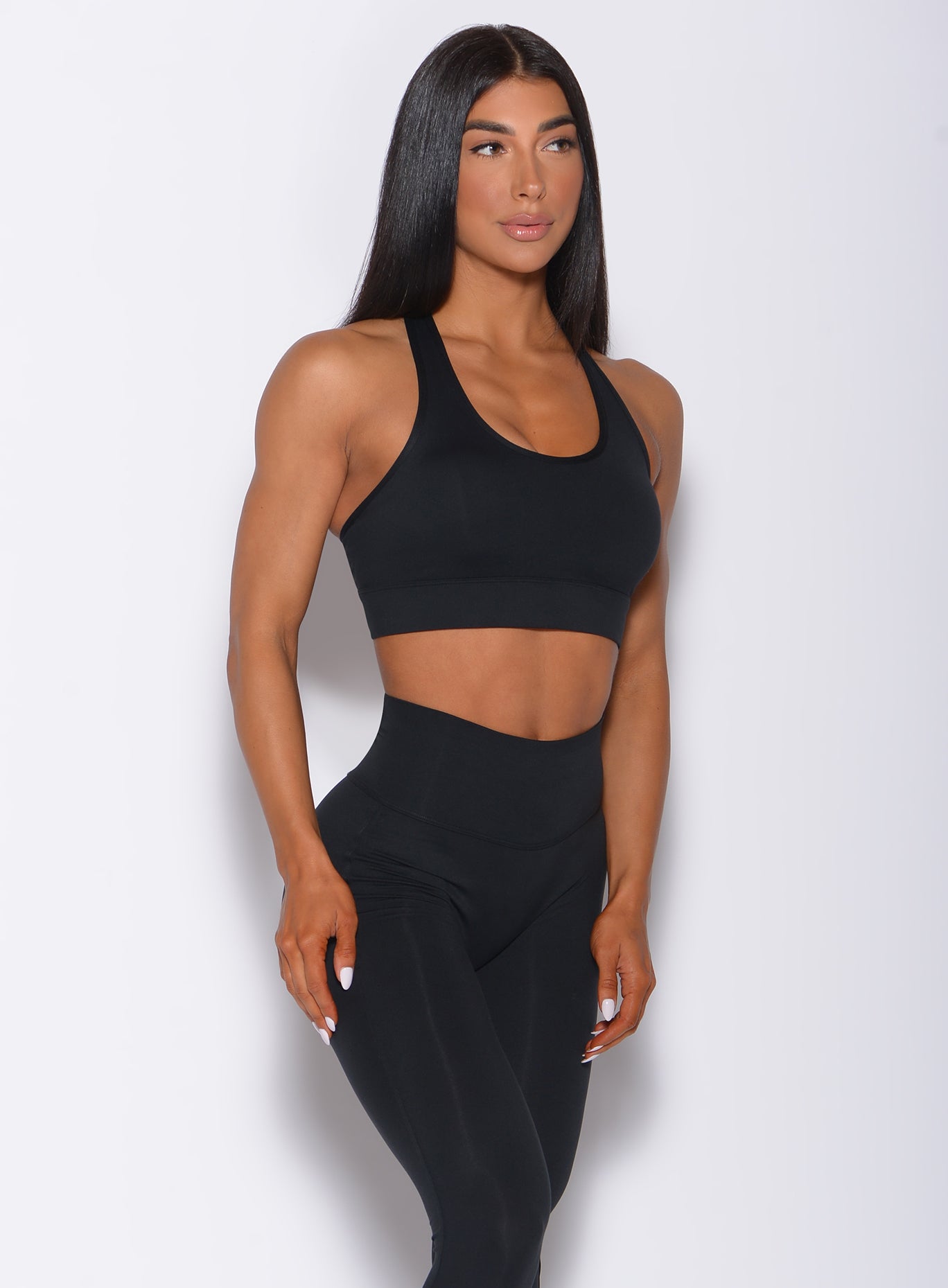 Front profile view of a model wearing our black rival sports bra and a matching sexy back leggings