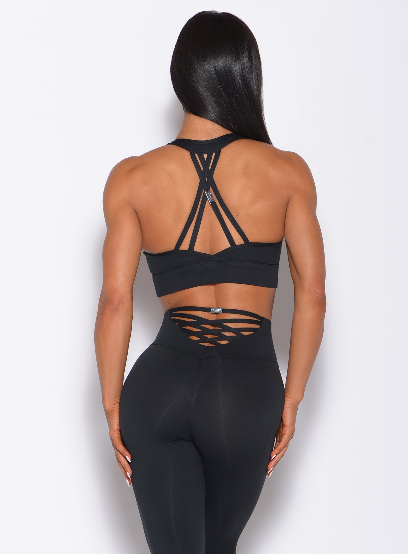 Back profile view of a model in our black rival sports bra and a matching leggings