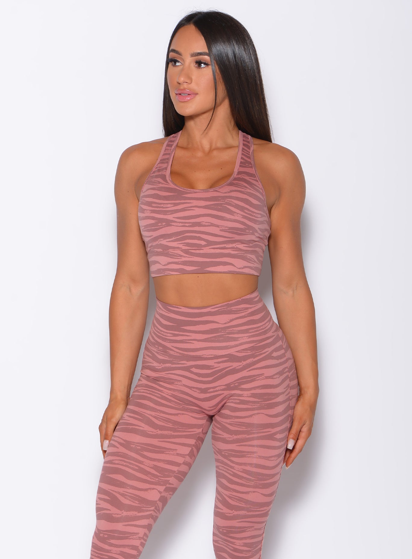 Front profile picture of a model wearing our rival sports bra in nude blush color and a matching sexy back leggings in tiger print