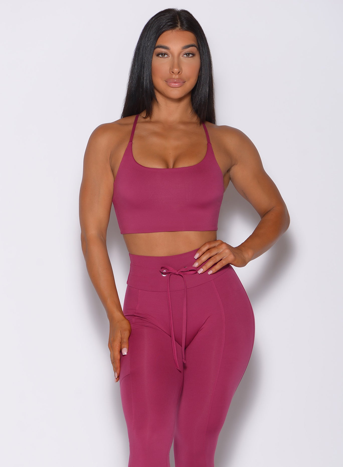Front profile view of a model in our cross fit sports bra in berry good color and a matching leggings