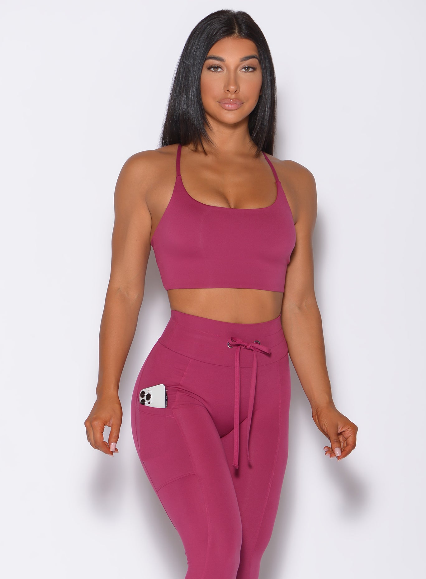 Front profile view of a model wearing our cross fit sports bra in berry good color and a matching leggings