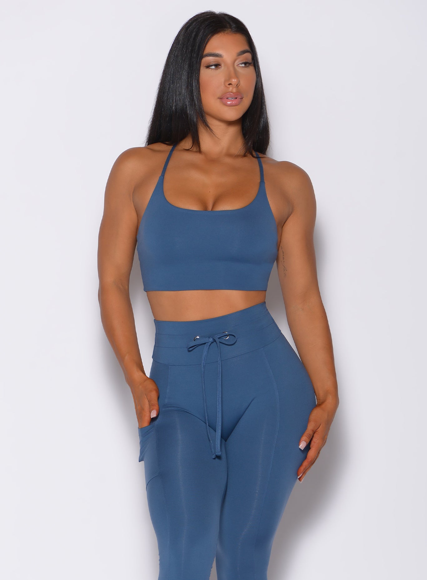 Front profile view of a model wearing our cross fit sports bra in cool water color and a matching leggings