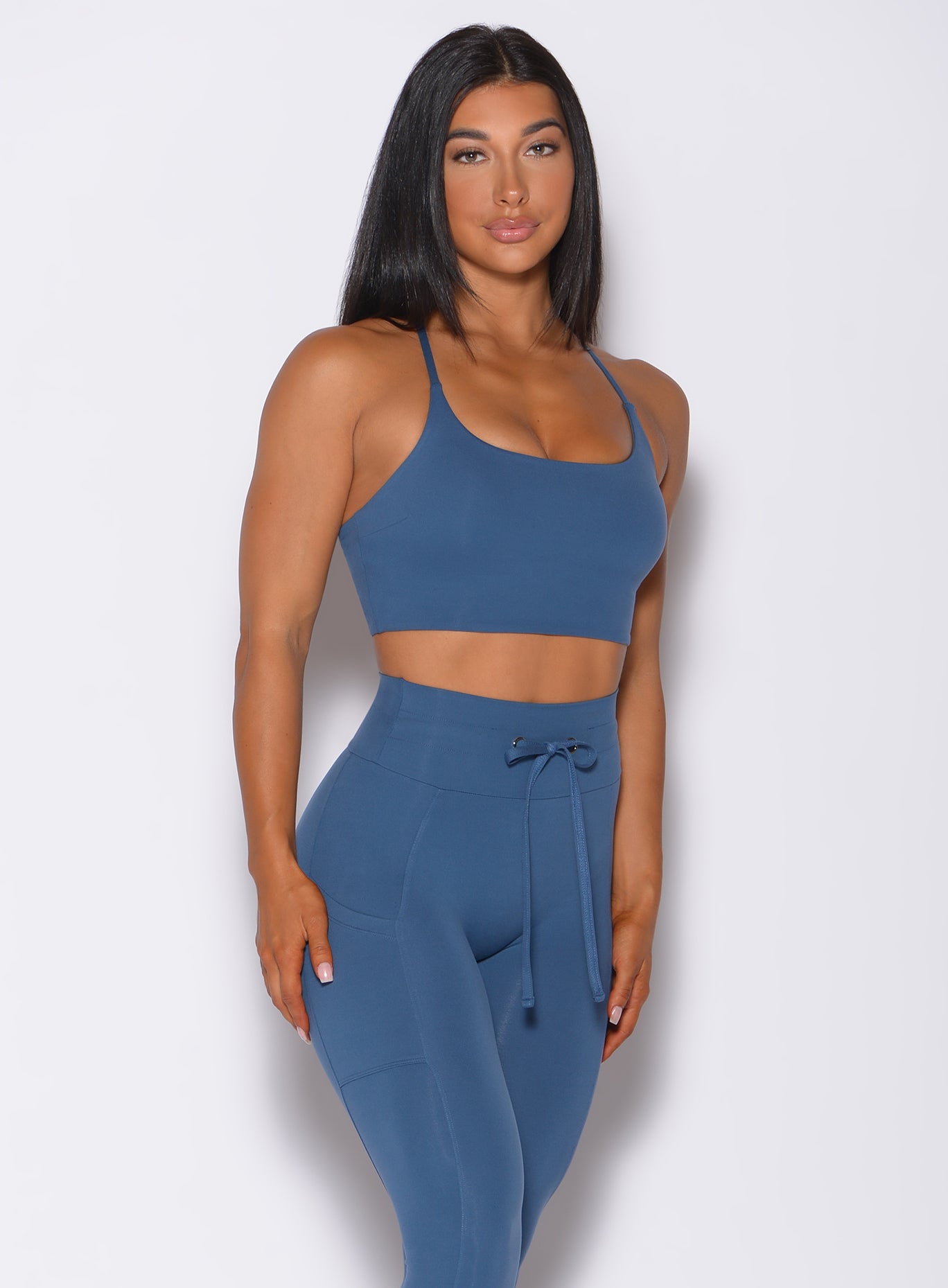 Front profile view of a model in our cross fit sports bra in cool water color and a matching leggings