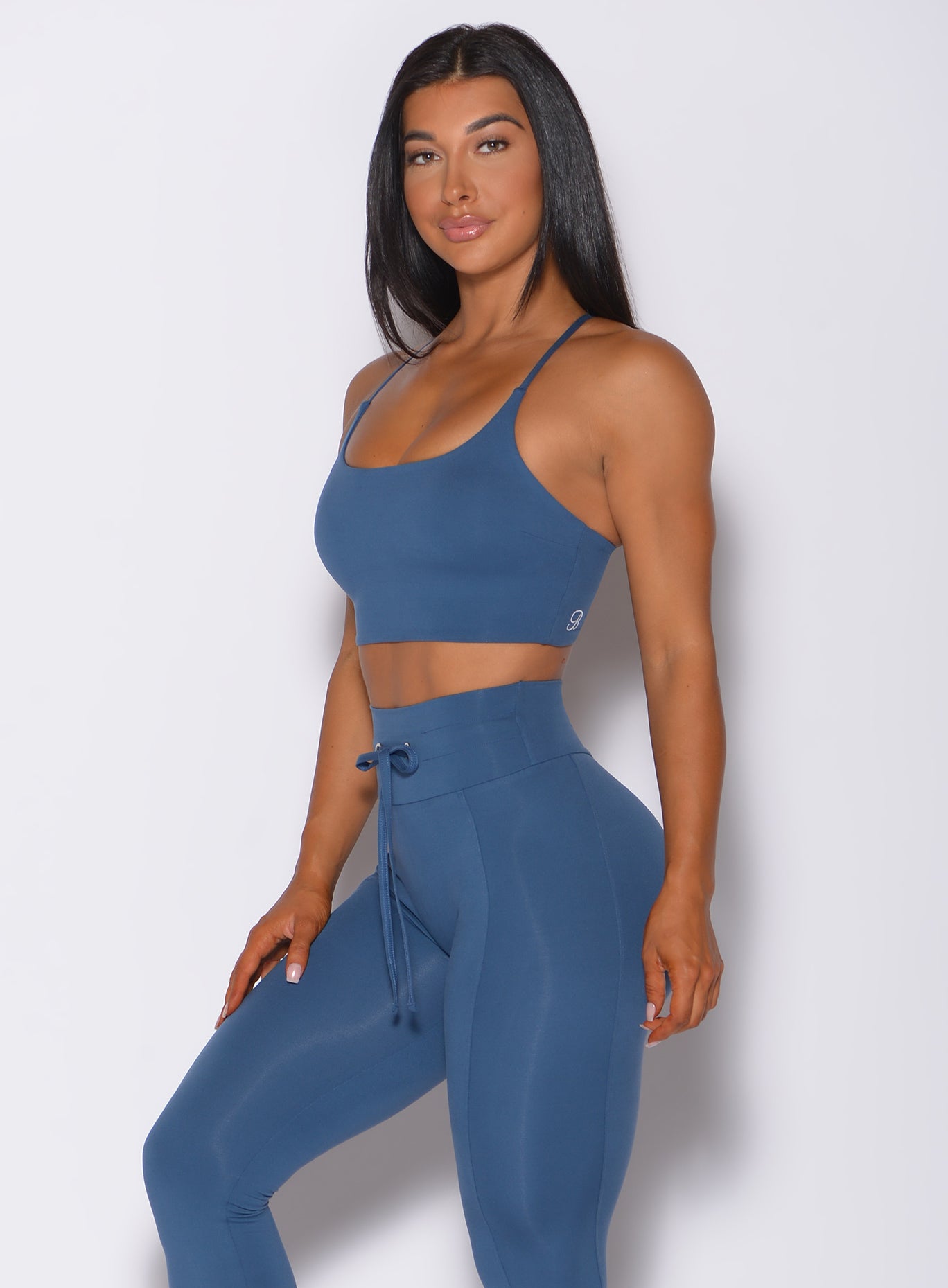 Left side profile view of a model angled left wearing our cross fit sports bra in cool water color and a matching leggings
