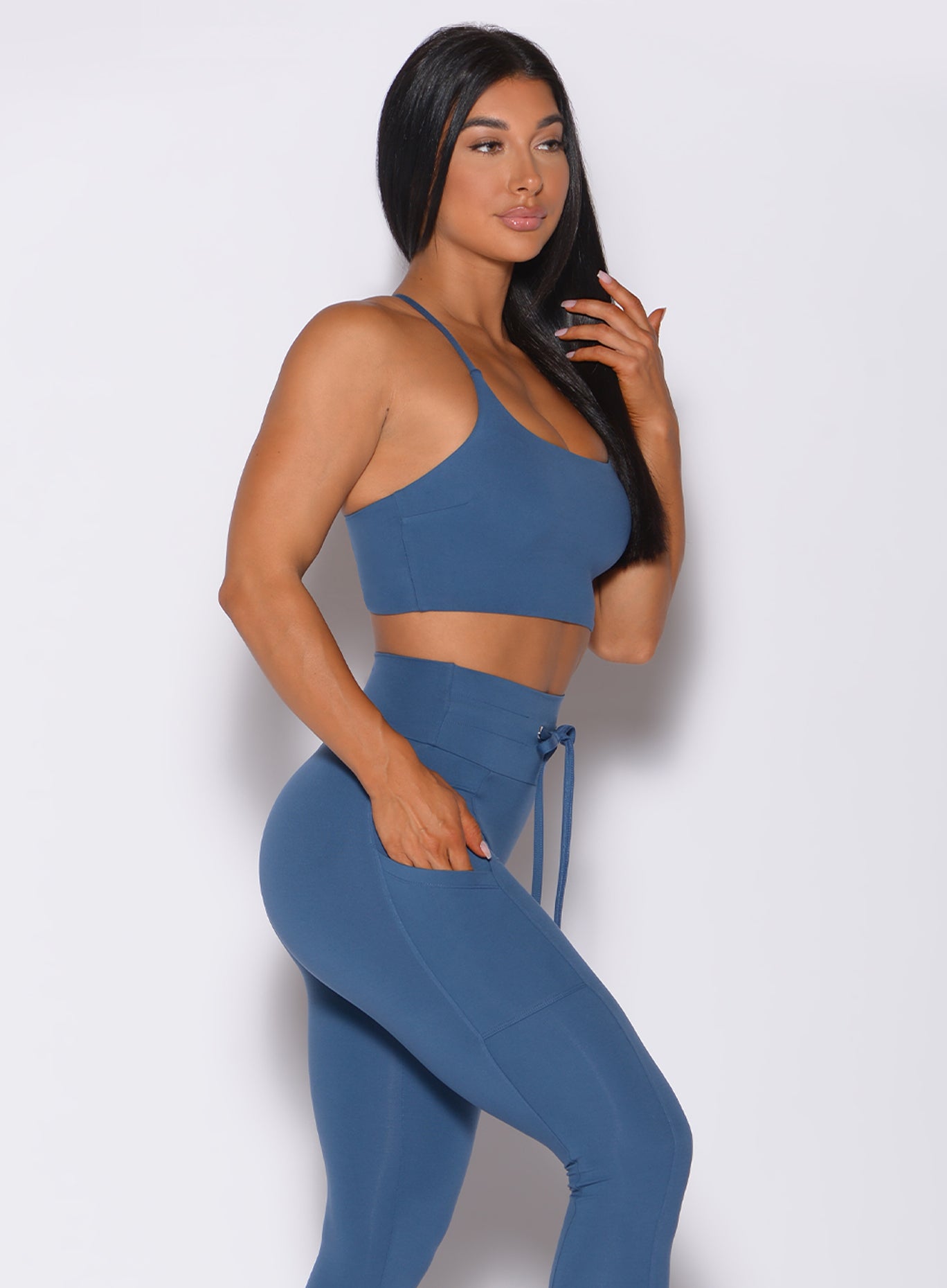 Right side profile view of a model wearing our cross fit sports bra in cool water color and a matching leggings