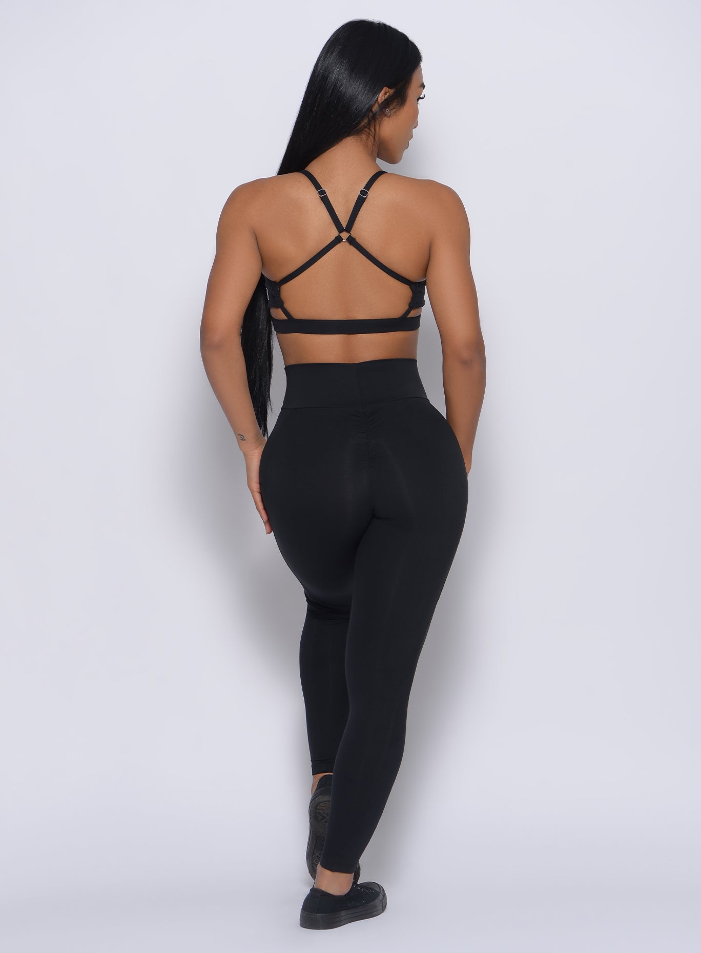Back profile view of a model wearing our black pumped sports bra and a matching leggings