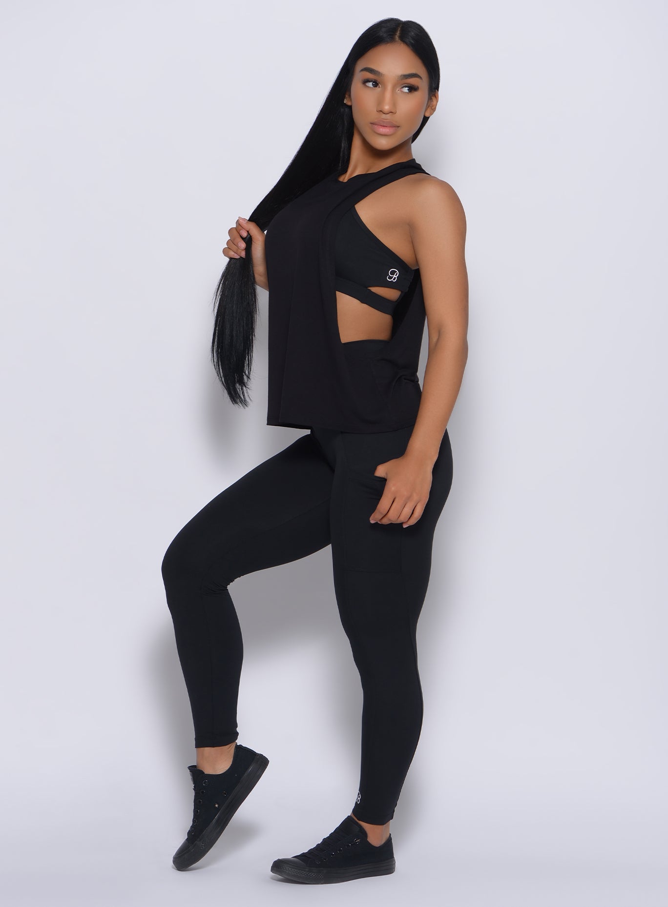 Left side profile view of a model facing to her left wearing our black muscle tank and a matching leggings