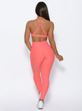  back profile of model wearing the Curve leggings and the Braid Back Sports Bra in Coral color