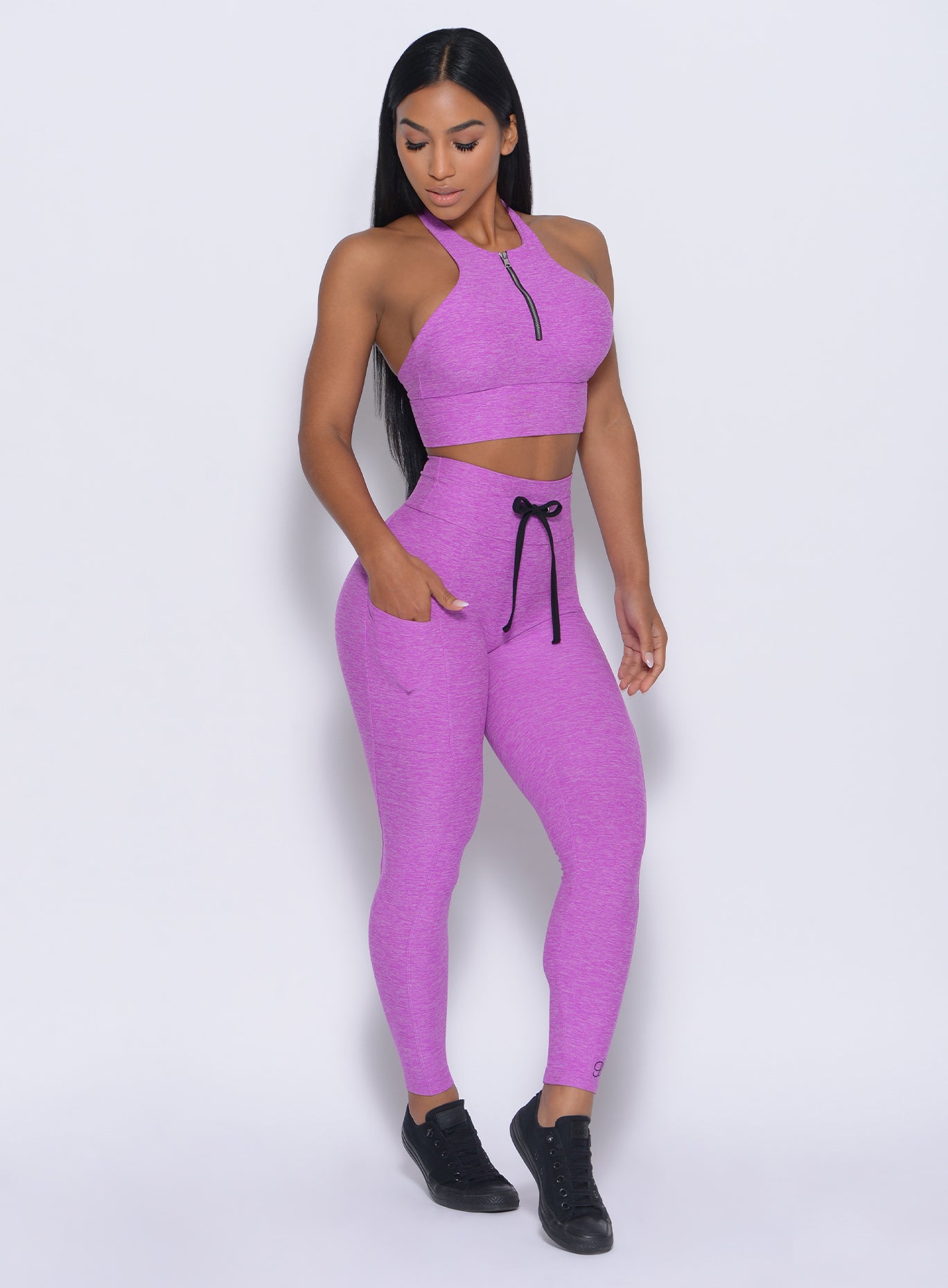 Front profile view of the model facing down wearing our thrive leggings in purple color and a matching bra 