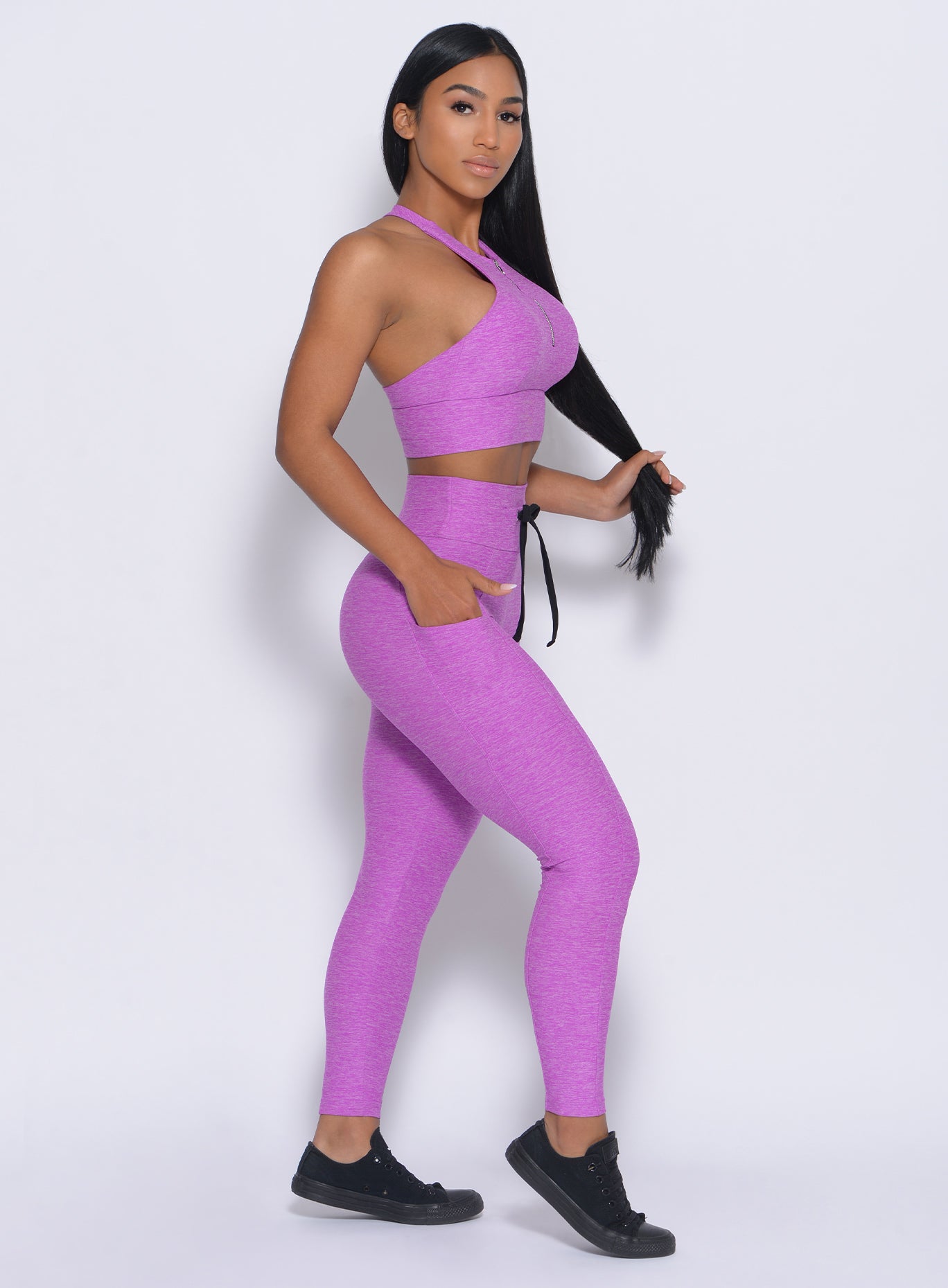 Right side view of the model facing to her right wearing our thrive leggings in purple color and a matching bra 