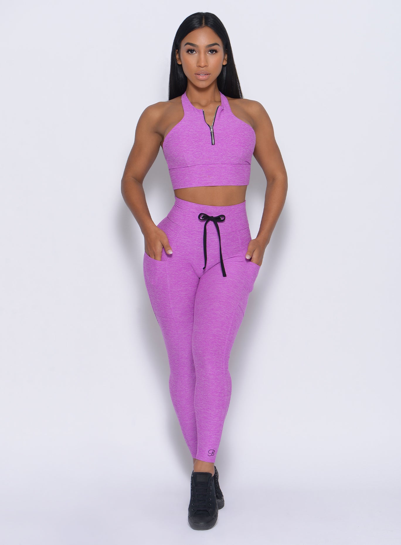 Front profile view of the model wearing our thrive leggings in purple color and a matching bra