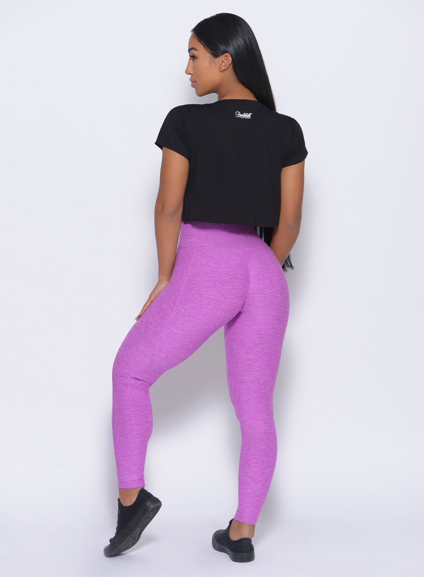 Back view of the model wearing our thrive leggings in purple color and a black top 