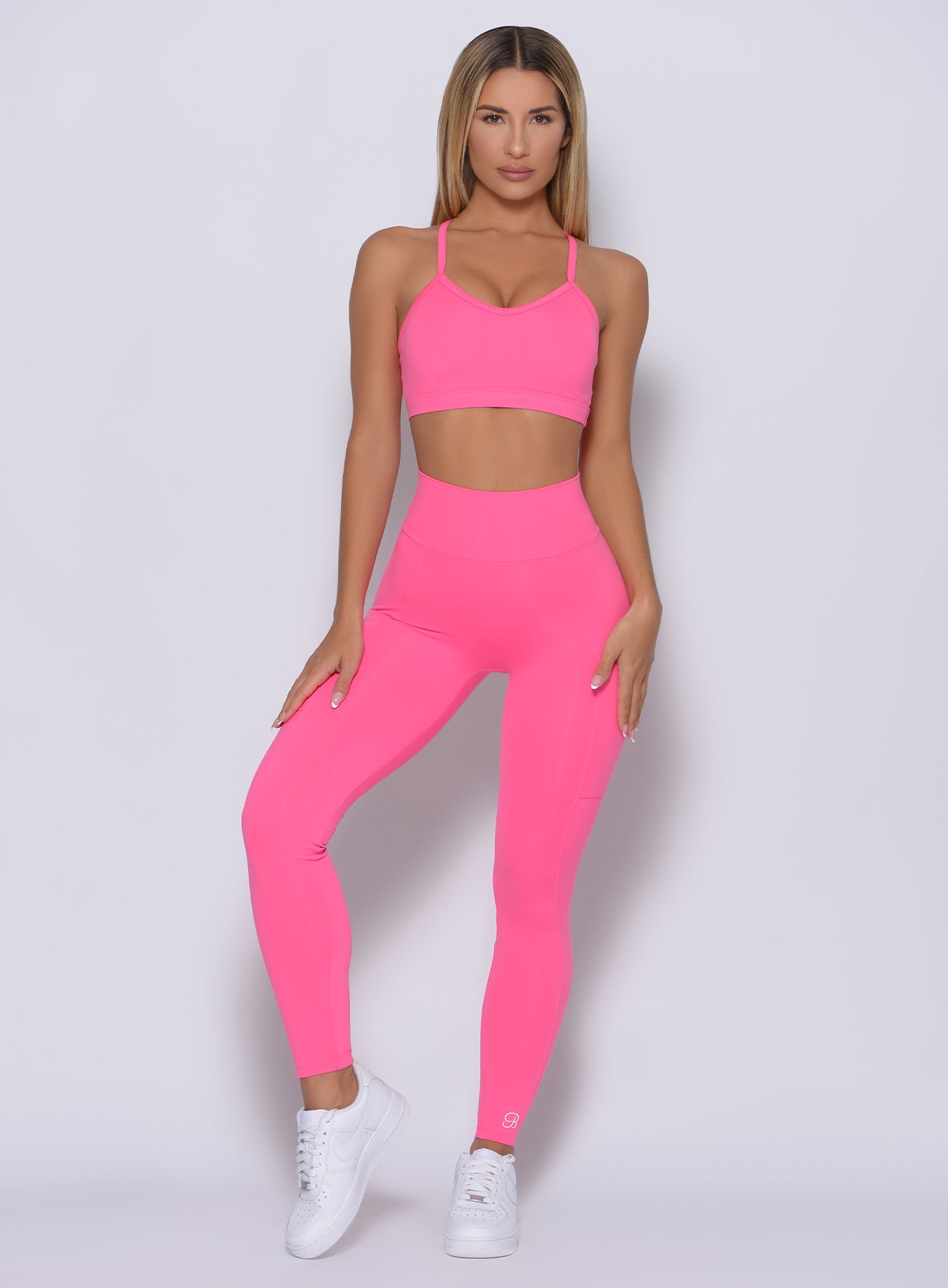 Front profile view of the model in our curves leggings in party pink color and a matching bra