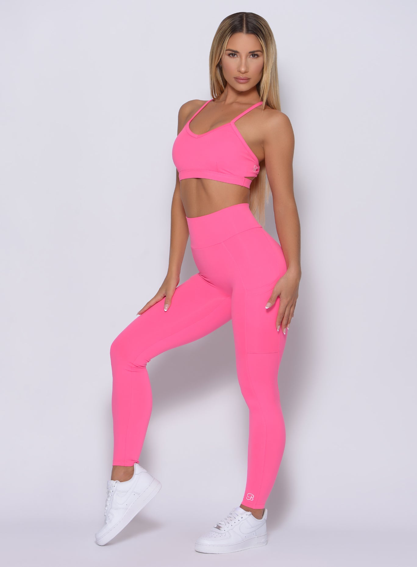 Left side view of the model facing forward wearing our curves leggings in party pink color and a matching bra