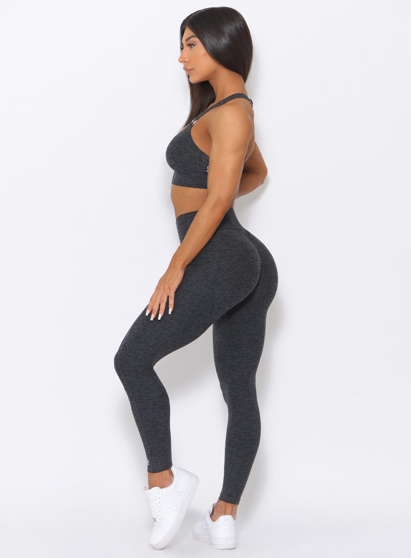Left side view of the model wearing our curves high waist leggings in charcoal color and a matching bra