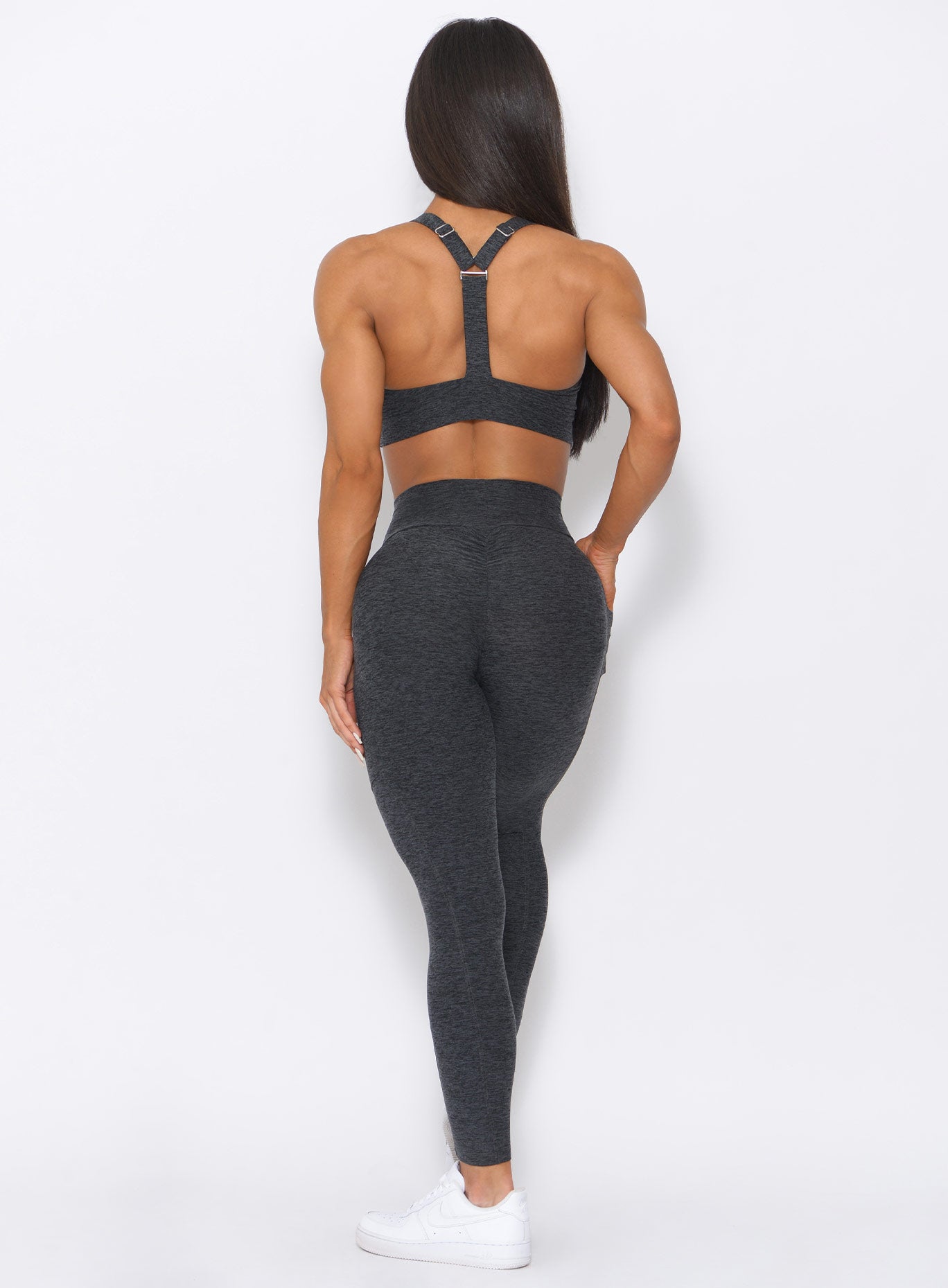Back view of the model wearing our curves high waist leggings in charcoal color and a matching bra