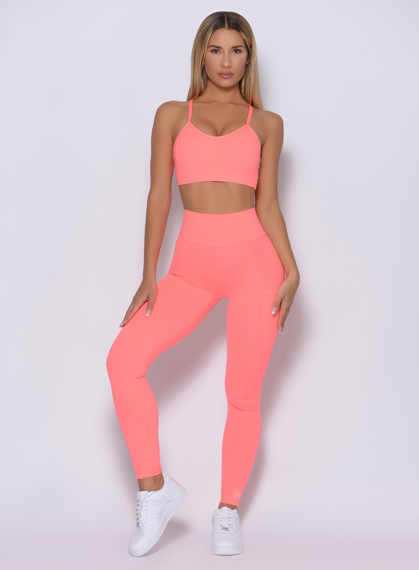 Model facing forward wearing our pumped sports bra in wild peach color and a matching leggings