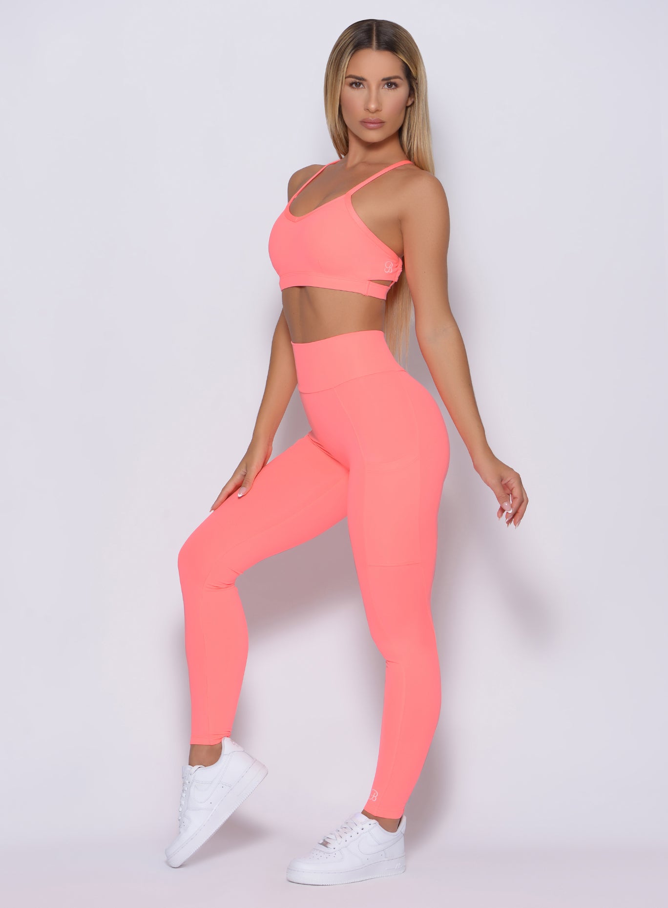 Left side view of the model angled left wearing our curves leggings in wild peach color and a matching bra