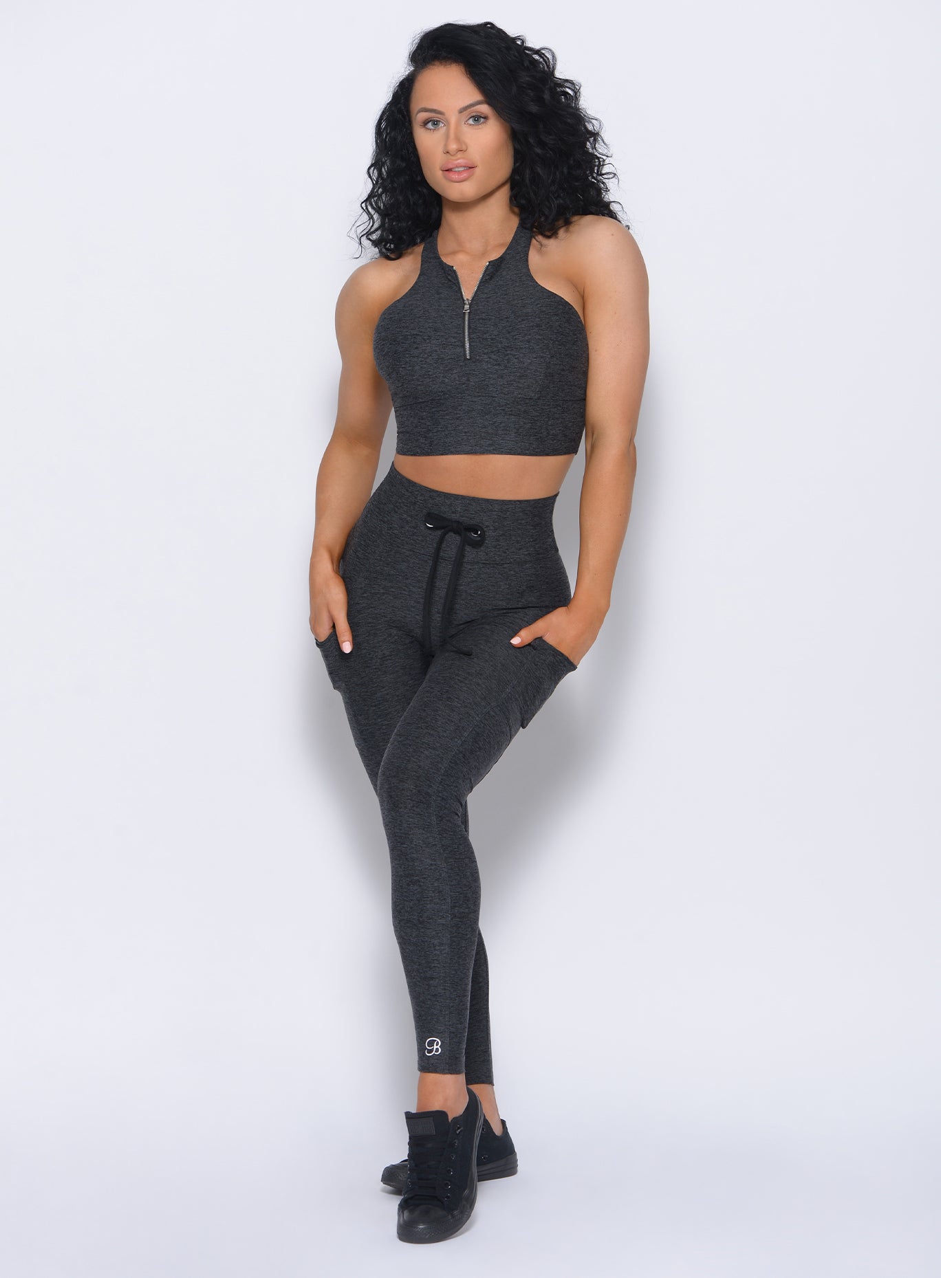 Front profile view of the model in our thrive leggings in charcoal color and a matching bra 
