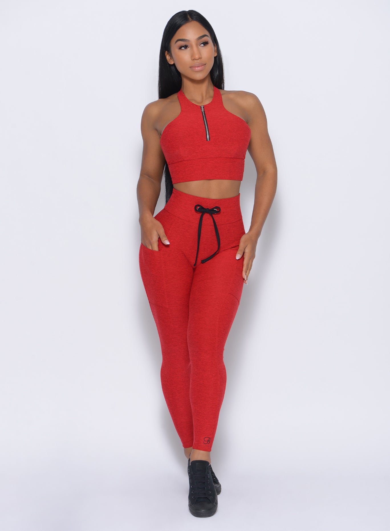 Front profile view of the model wearing our thrive leggings in sunset red color and a matching bra 
