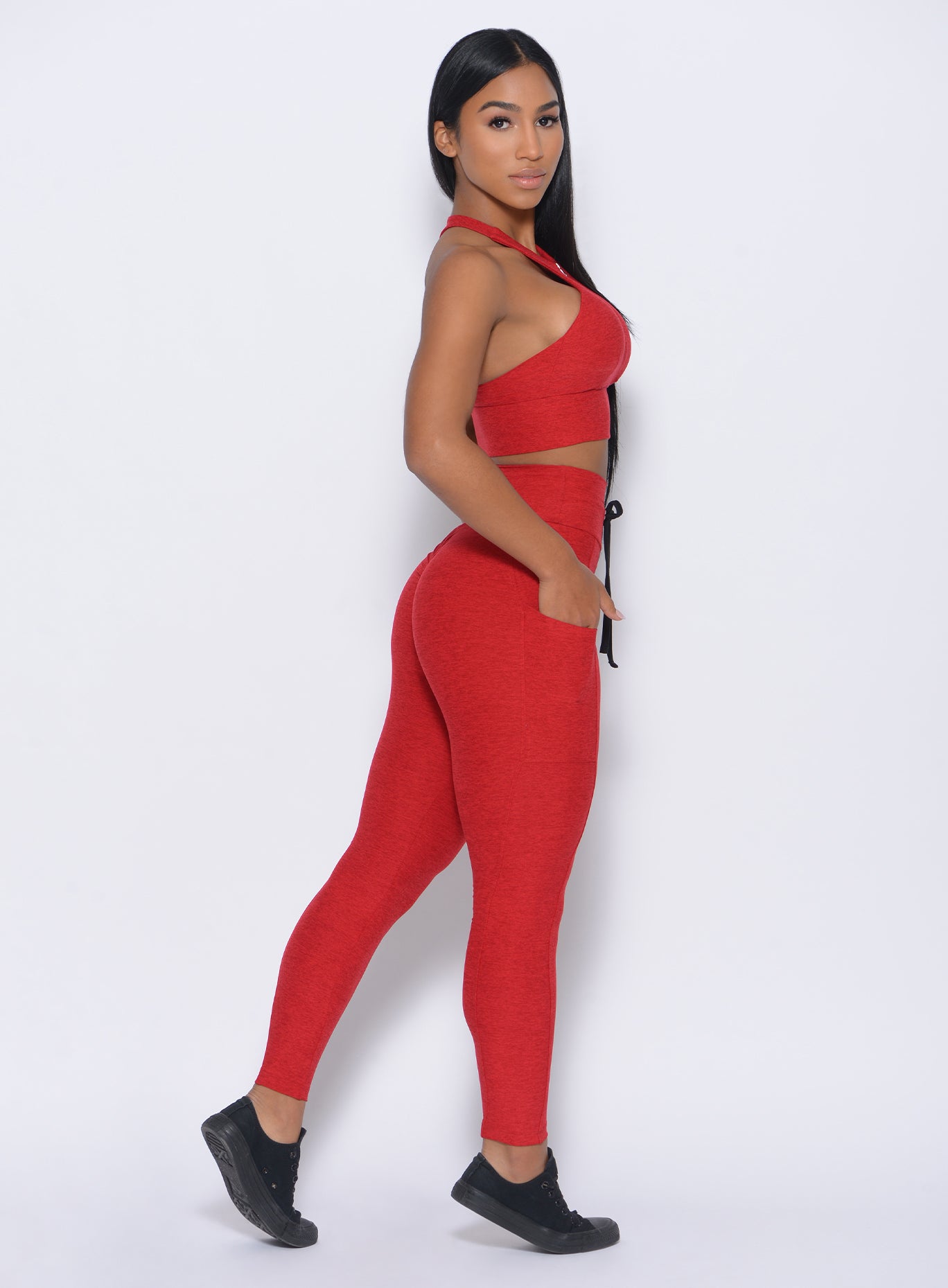 Right side view of the model wearing our thrive leggings in sunset red color and a matching bra