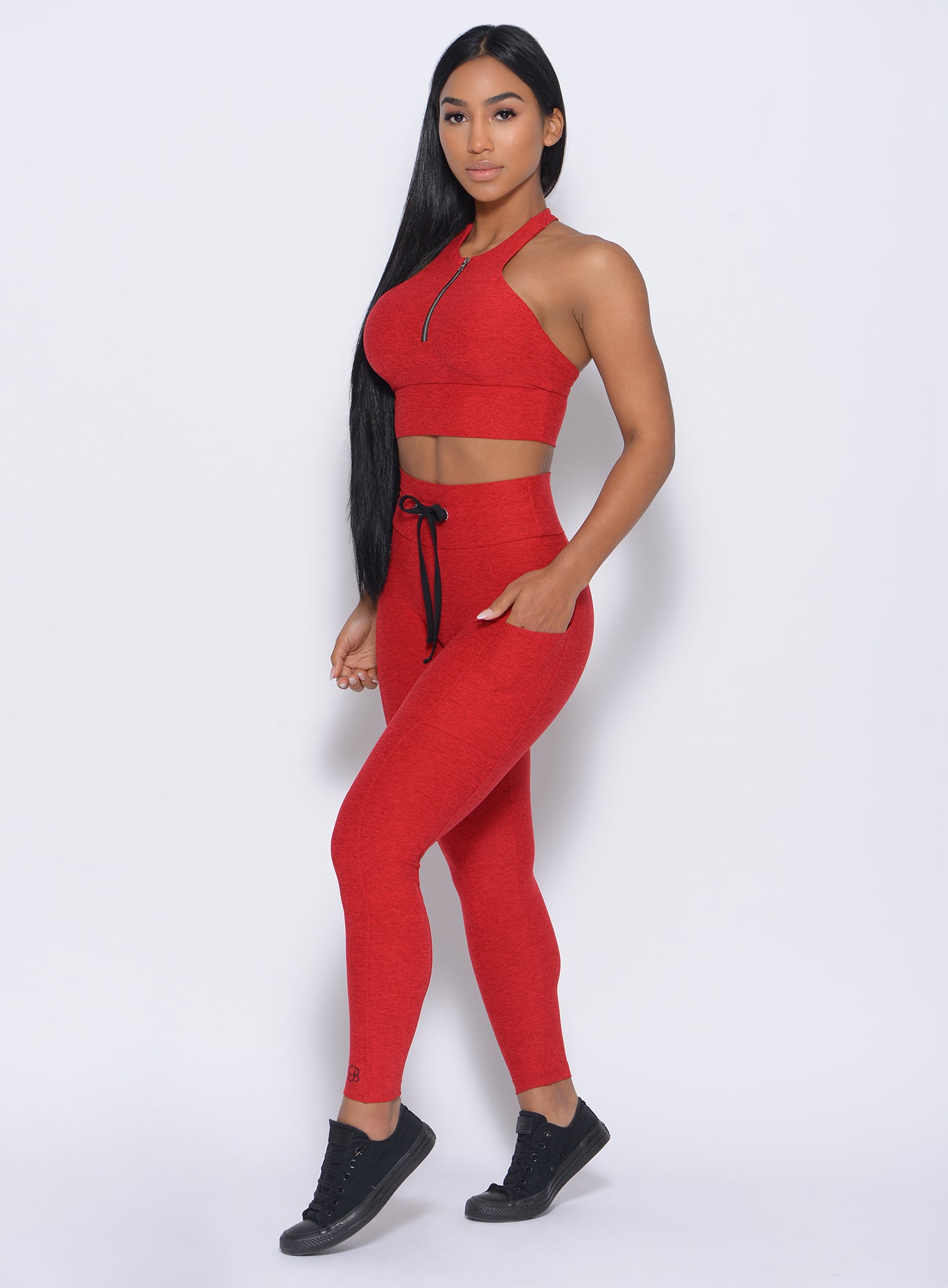 Left side view of the model  angled left wearing our thrive leggings in sunset red color and a matching bra