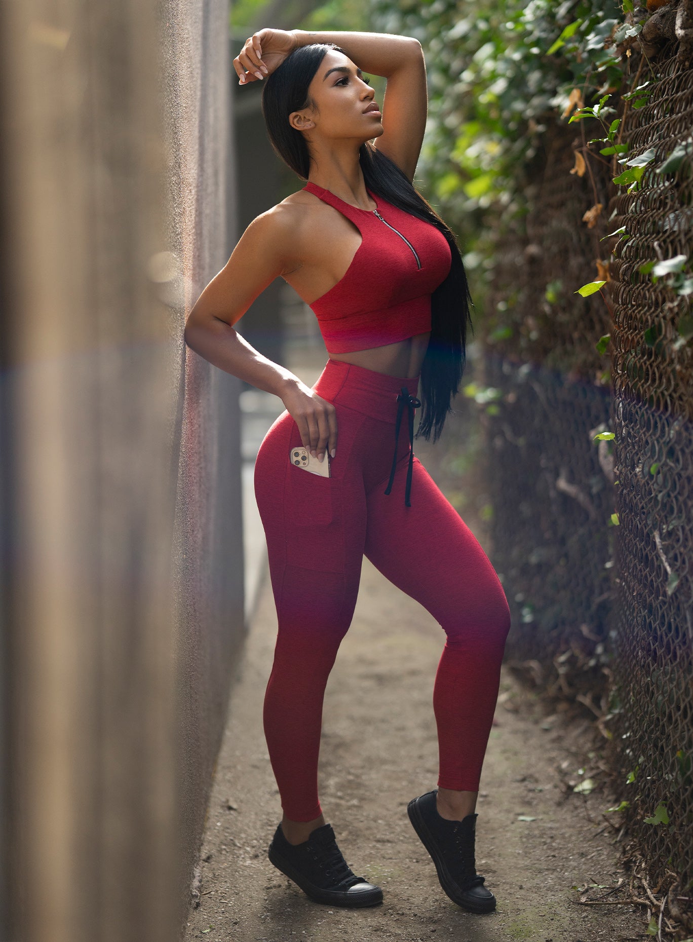 Right side view of the model in our thrive leggings in sunset red color and a matching bra
