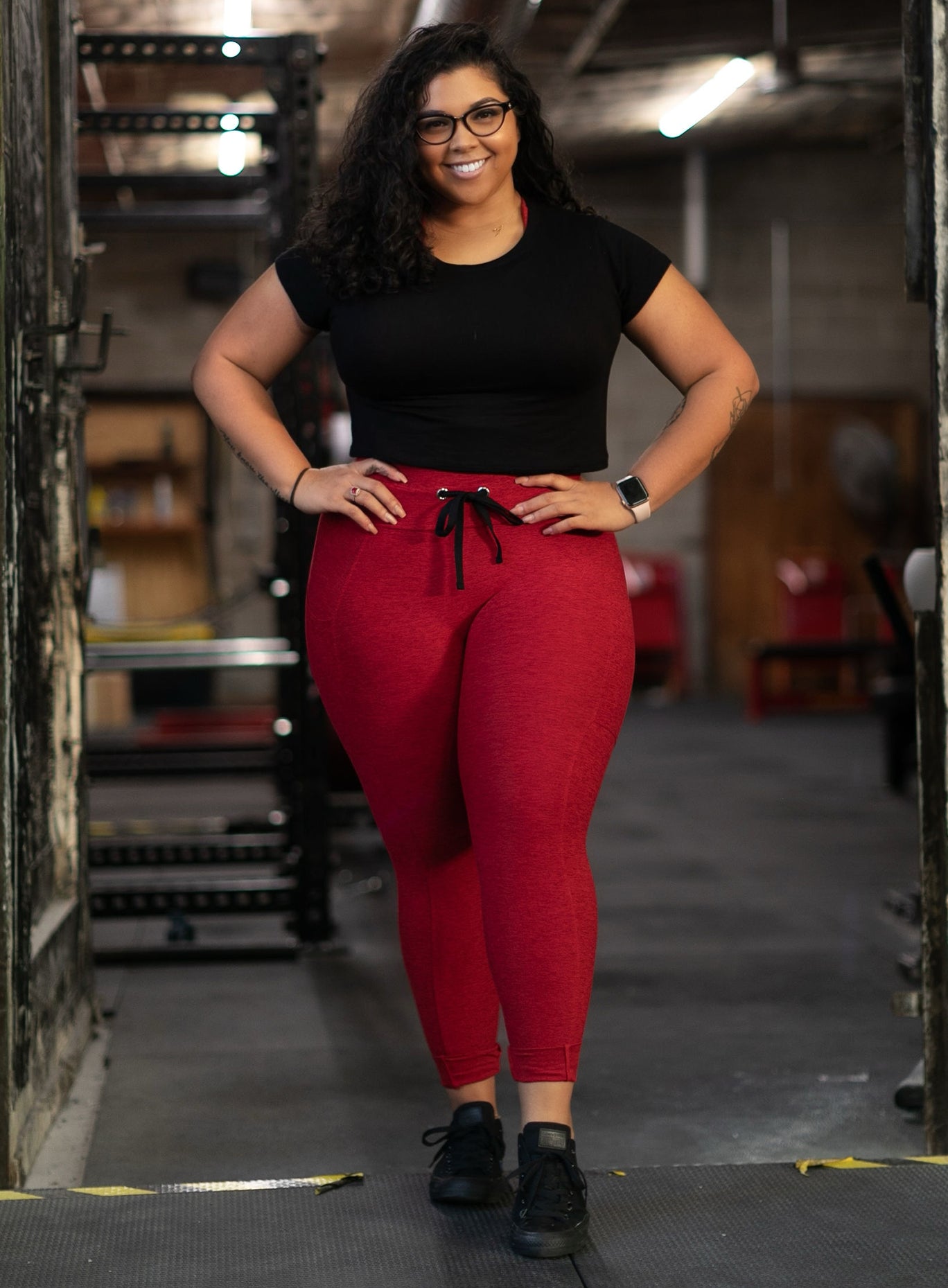 Model facing forward in our thrive leggings in sunset red color and a black top 