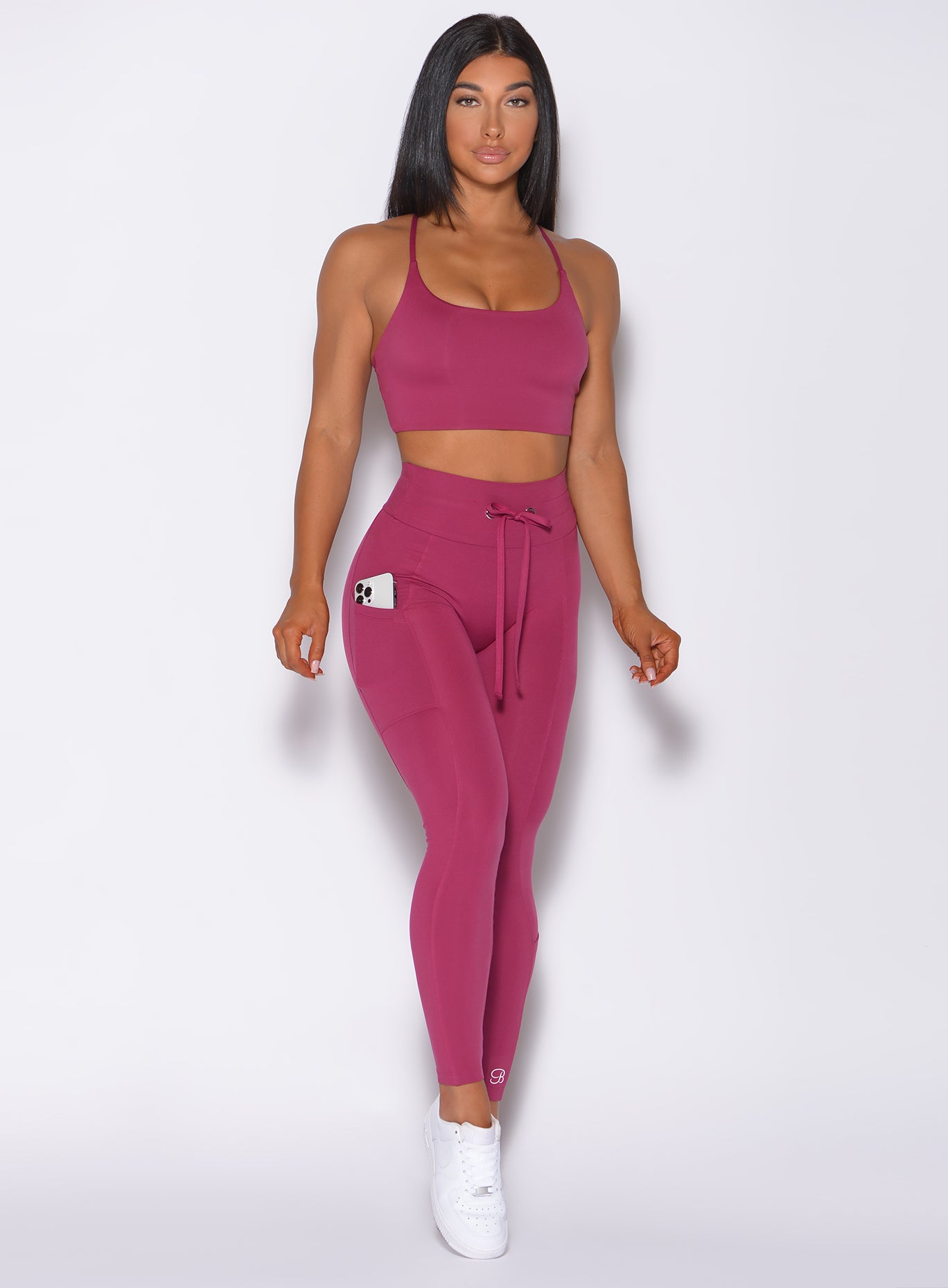 Front profile view of a model in our empower leggings in berry good color and a matching bra 