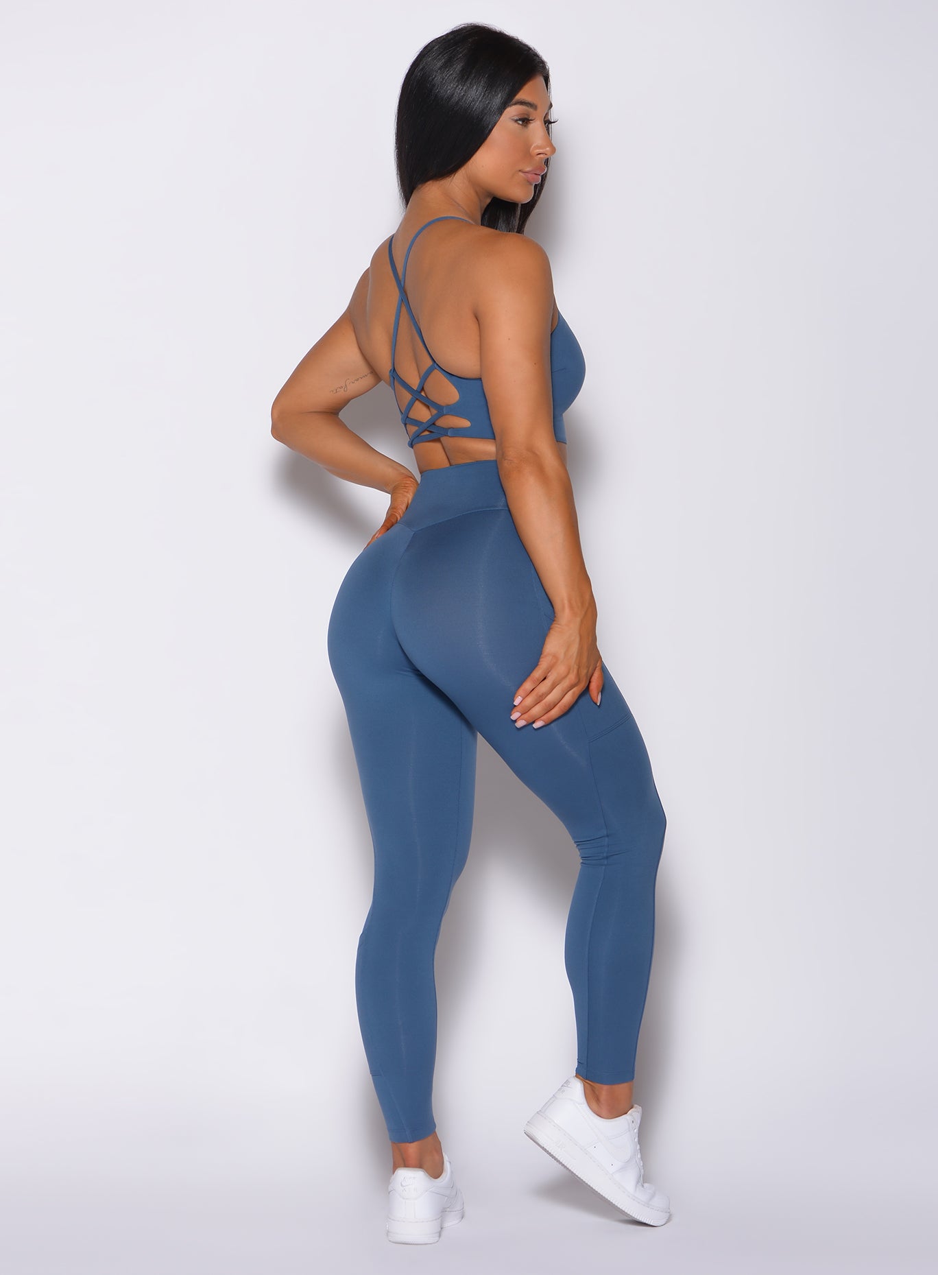 Right side profile view of a model in our empower leggings in cool water color and a matching bra