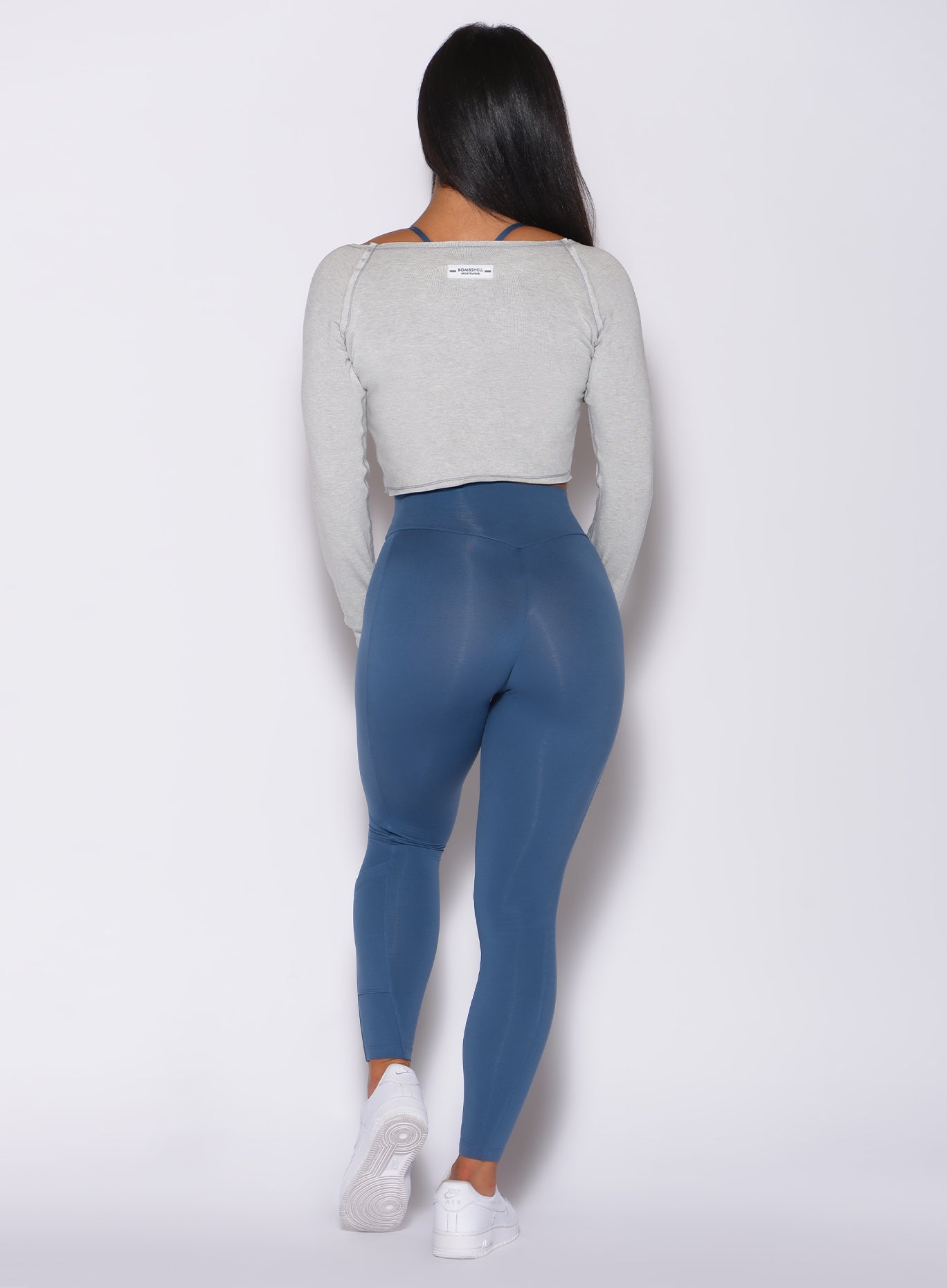Back profile view of a model in our bamboo pullover in beach sand color and a blue leggings
