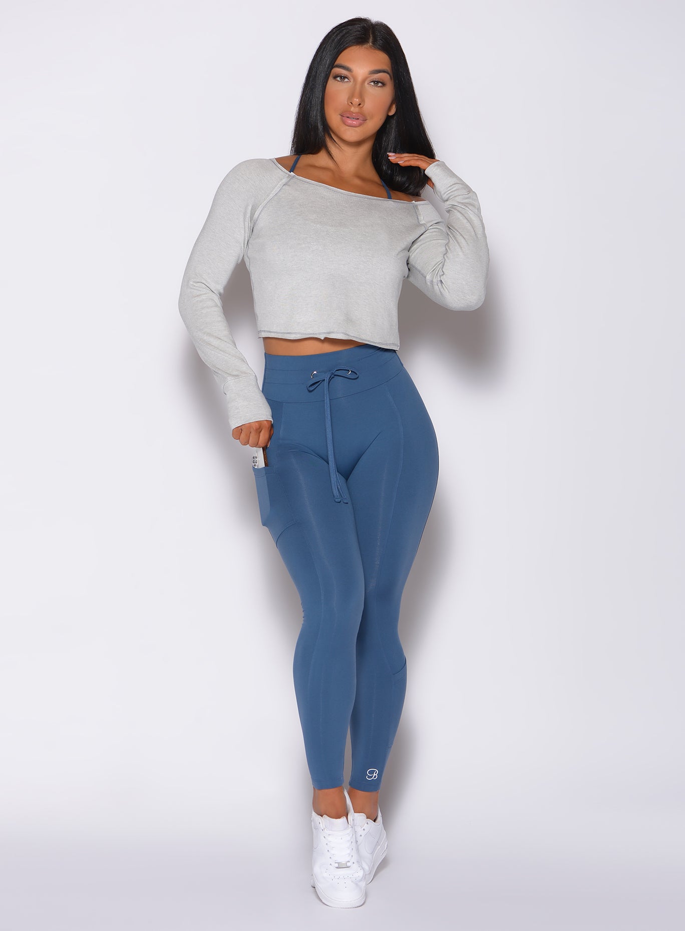 Front profile view of a model in our bamboo pullover in beach sand color and a high waisted blue leggings 
