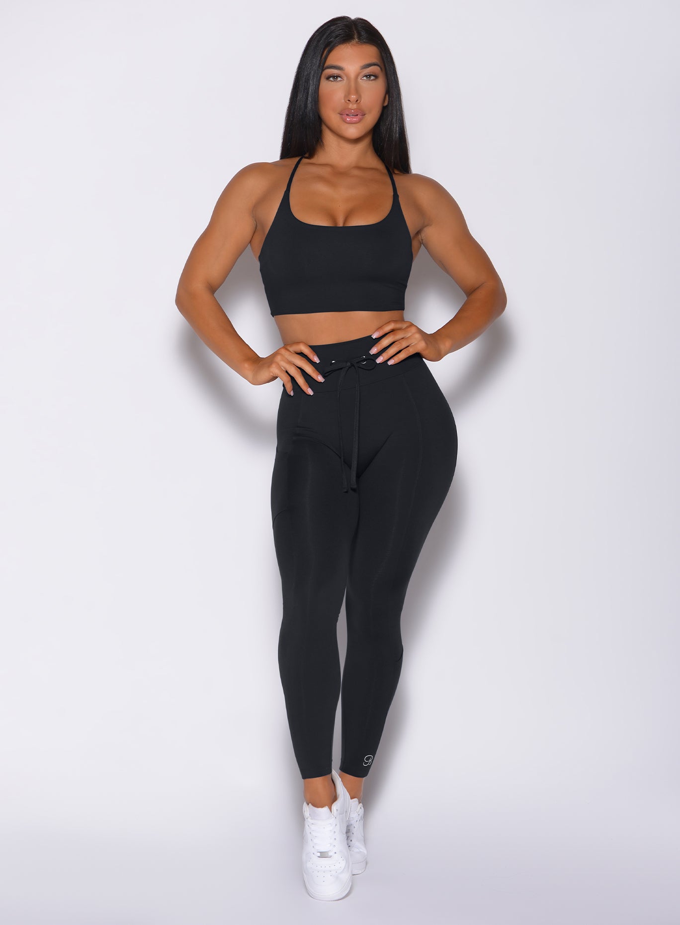 Front profile view of a model wearing our black empower leggings and a matching bra 