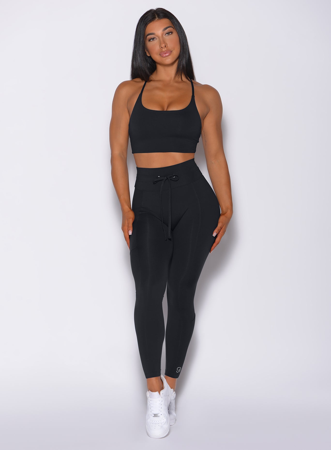 Model facing forward wearing our black empower leggings and a black bra 