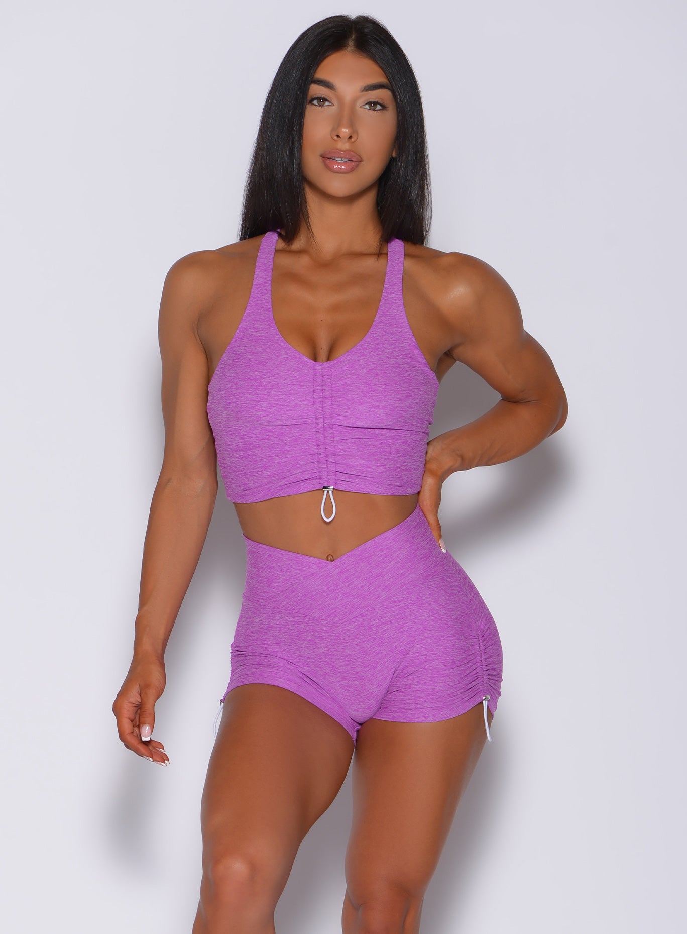 Front profile view of a model wearing our enhance toggle bra in purple rain color and a matching shorts