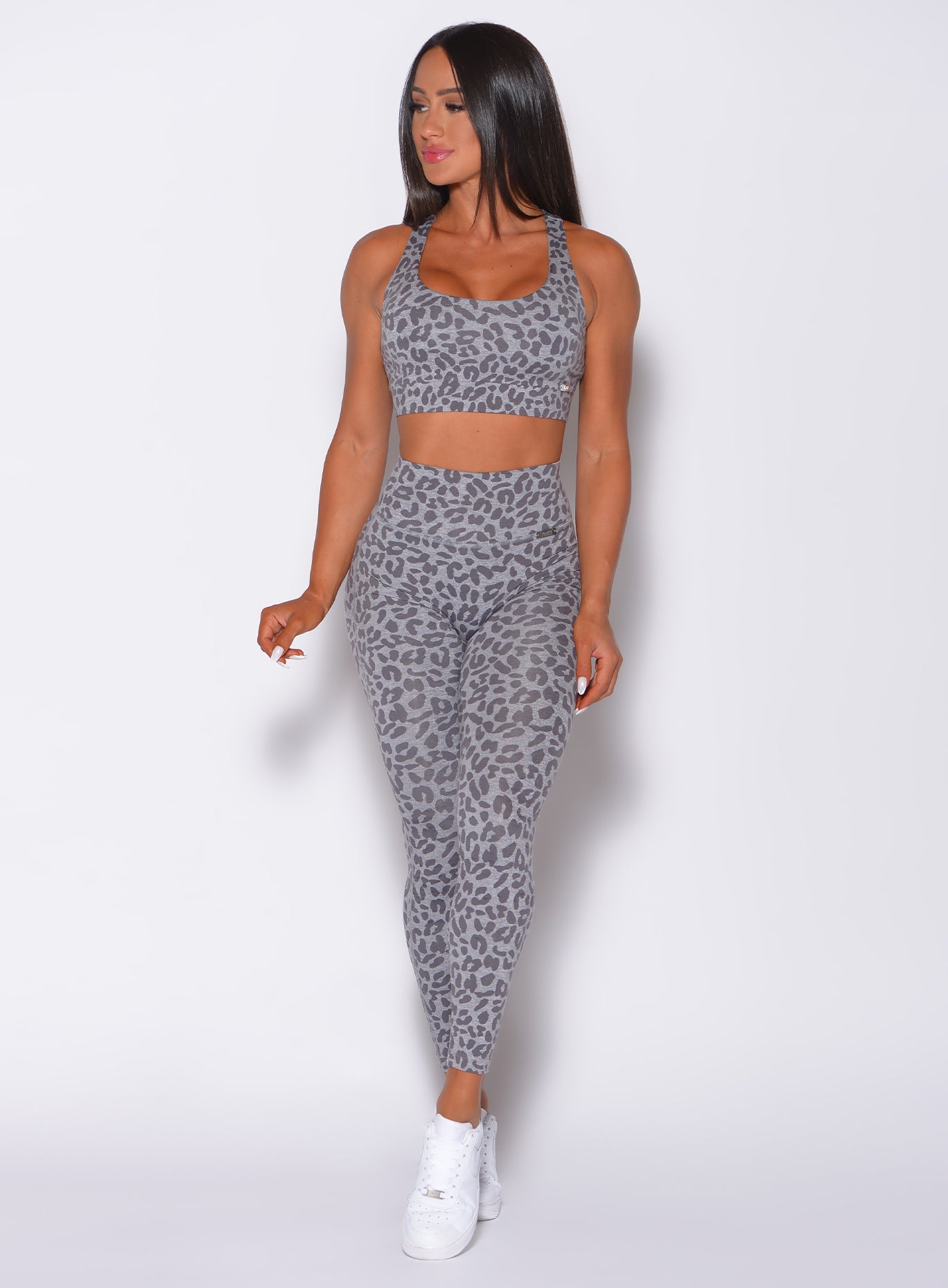Front profile view of a model facing to her right wearing our fit cheetah leggings in lightning gray color and a matching bra