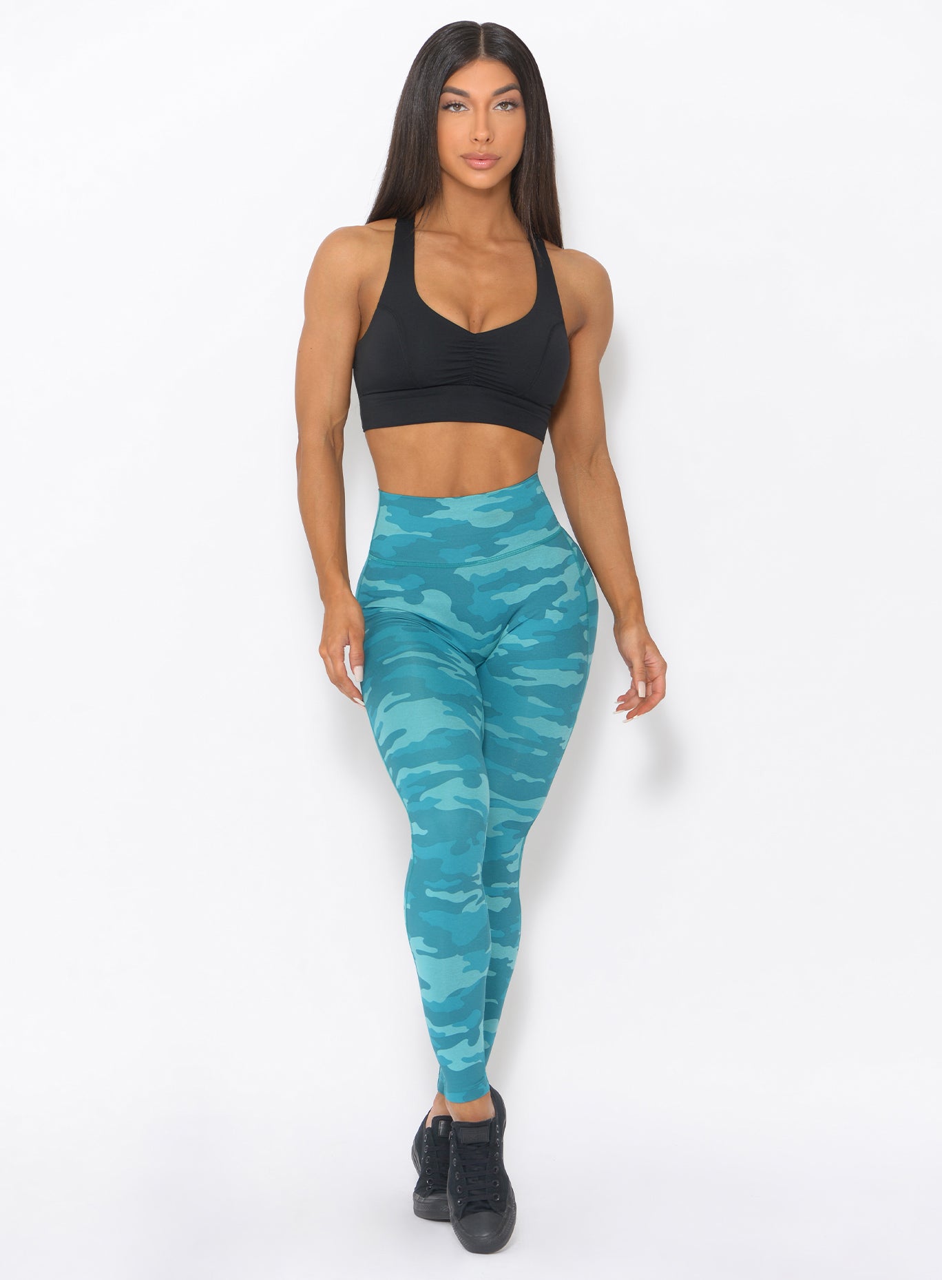 Front profile view of the model wearing our fit camo leggings in teal color and a black sports bra