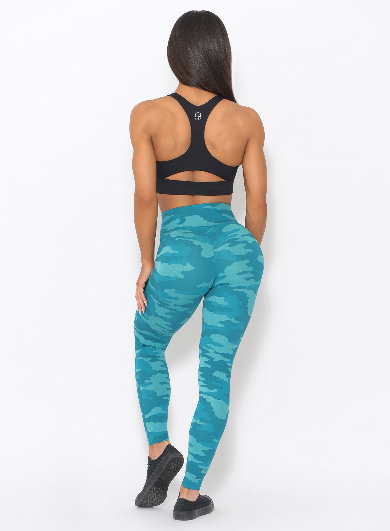 Back view of the model wearing our fit camo leggings in teal color and a black sports bra
