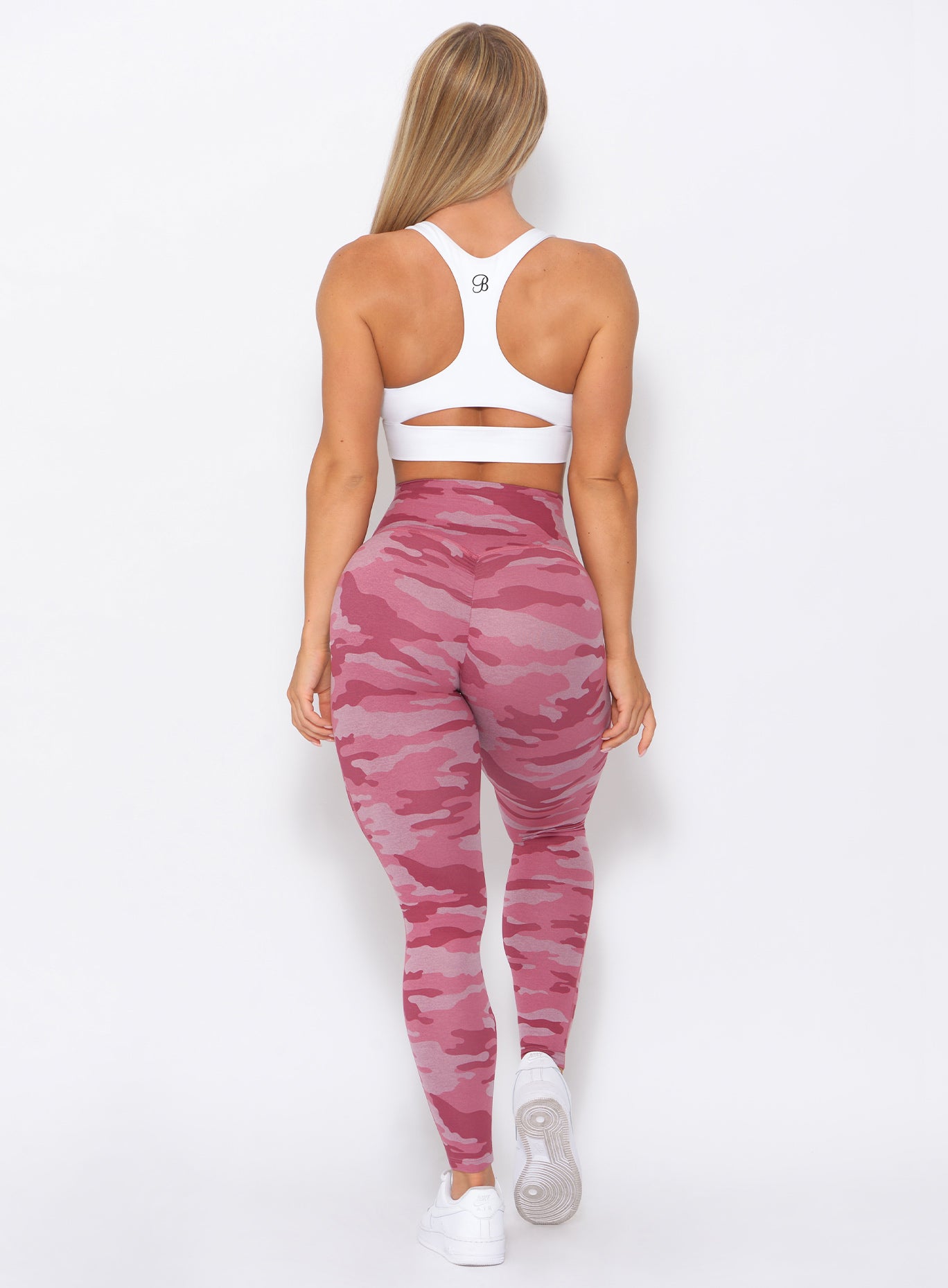 Back of the model wearing our fit camo leggings in hibiscus camo color and a white bra