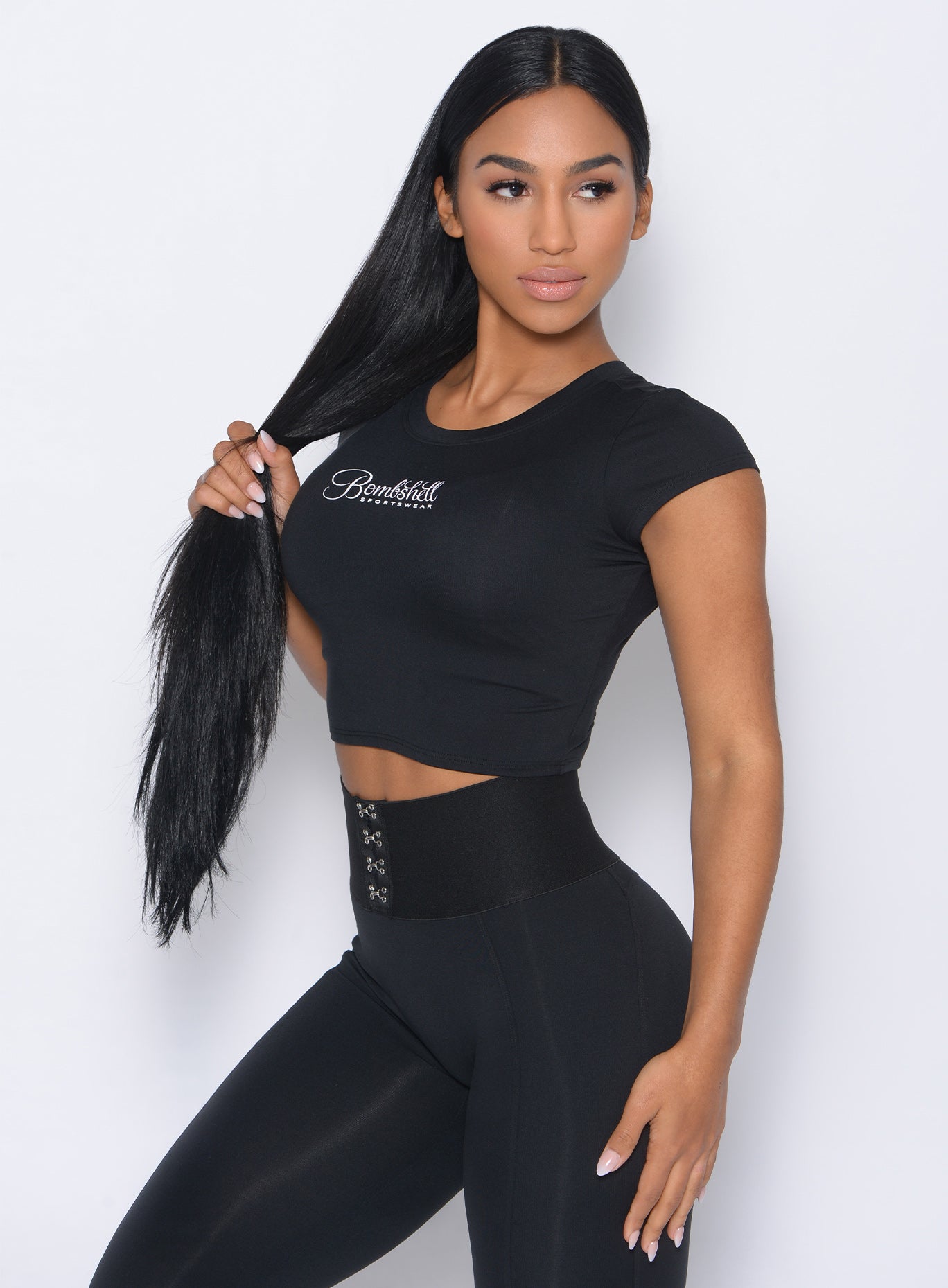 Left side of the model angled left in our black fit fam tee and a matching leggings