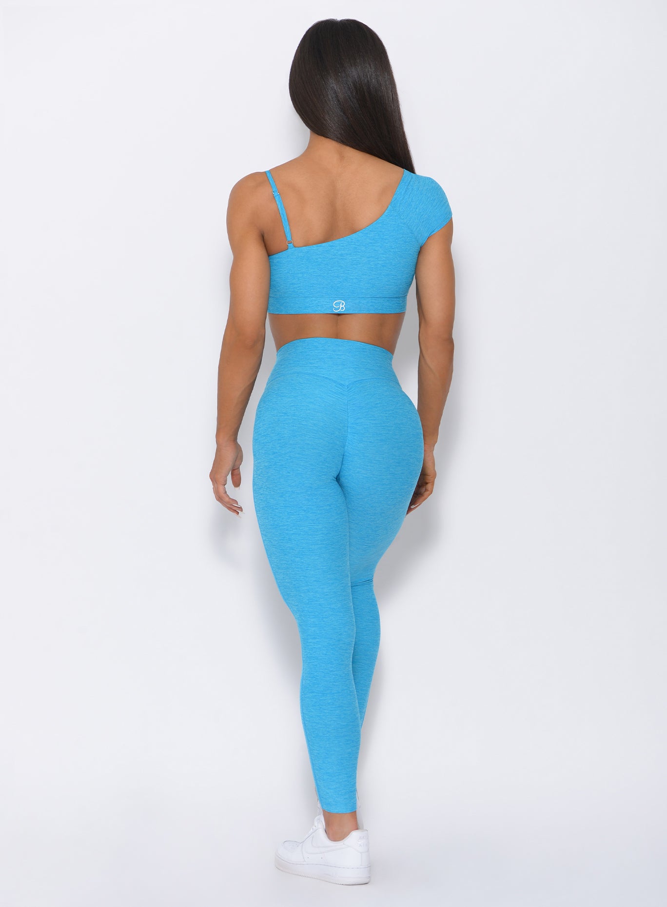 Back profile view of the model in our high waist fit leggings in icy blue and a matching bra
