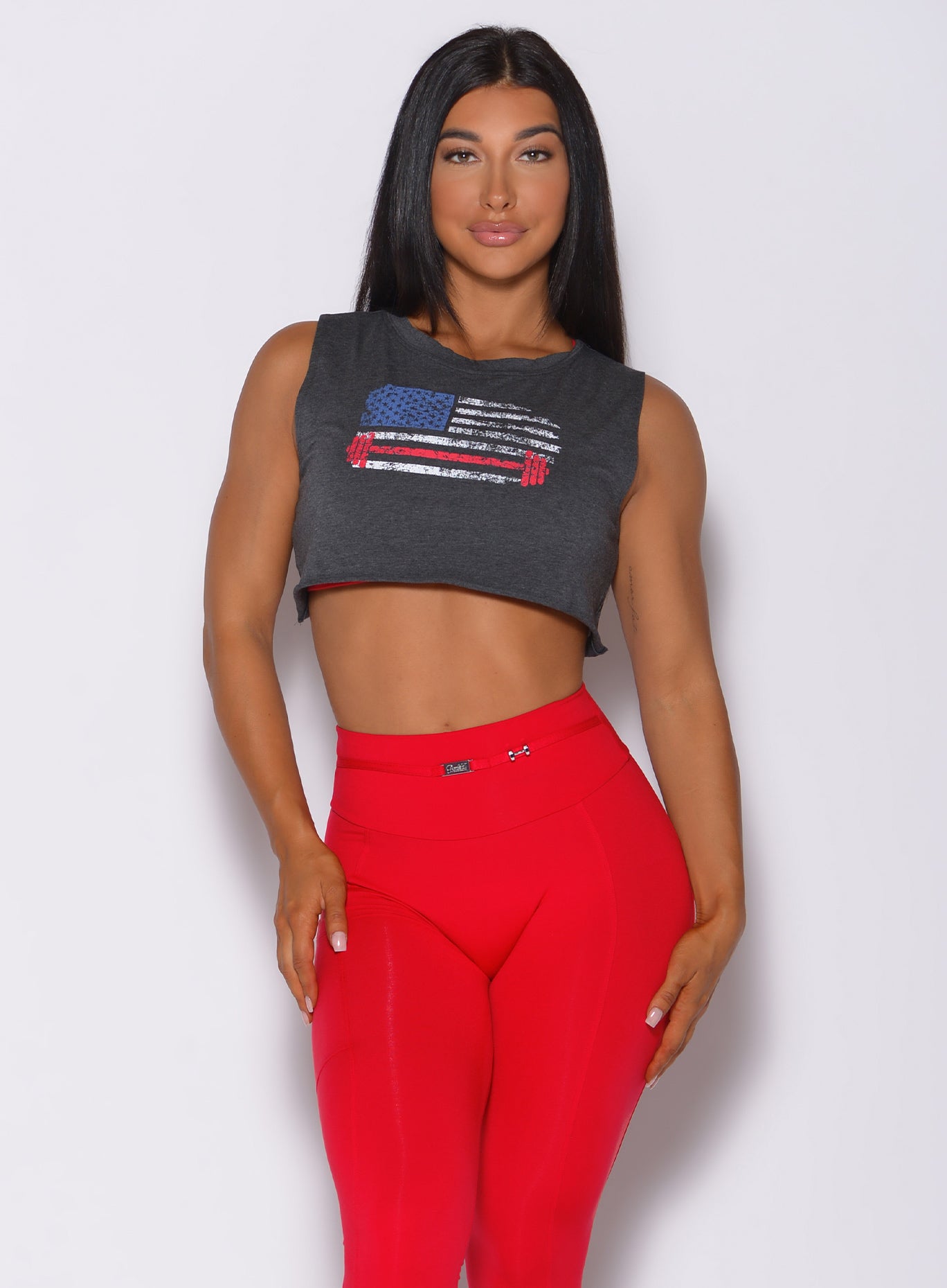 Front profile view of a model wearing our USA barbell tank in charcoal color and a red leggings
