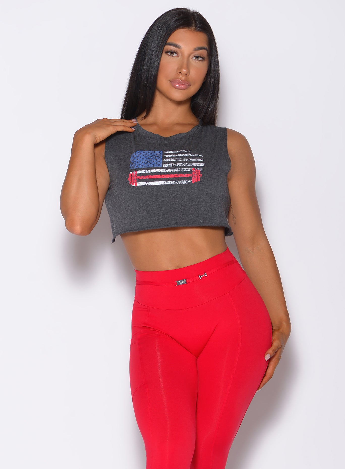 Front profile view of a model in our USA barbell tank in charcoal color and a red leggings 