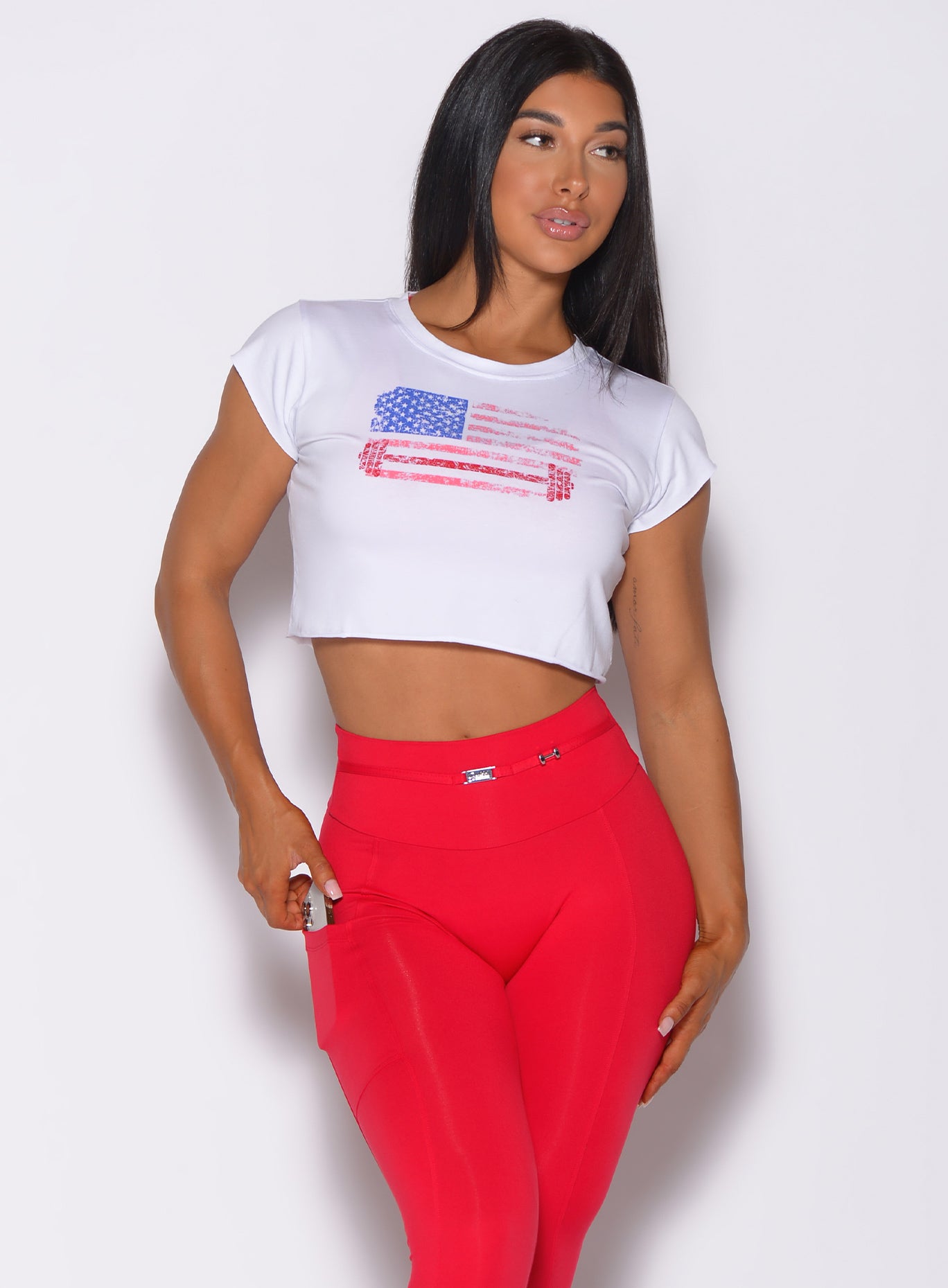 Front profile view of a model facing to her left wearing our white USA Barbell tee and a red leggings