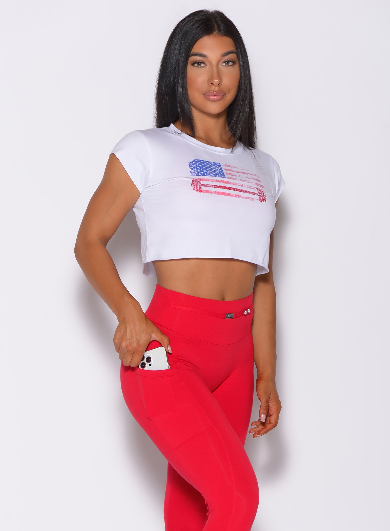 Front profile view of a model wearing our white USA Barbell tee and a red leggings