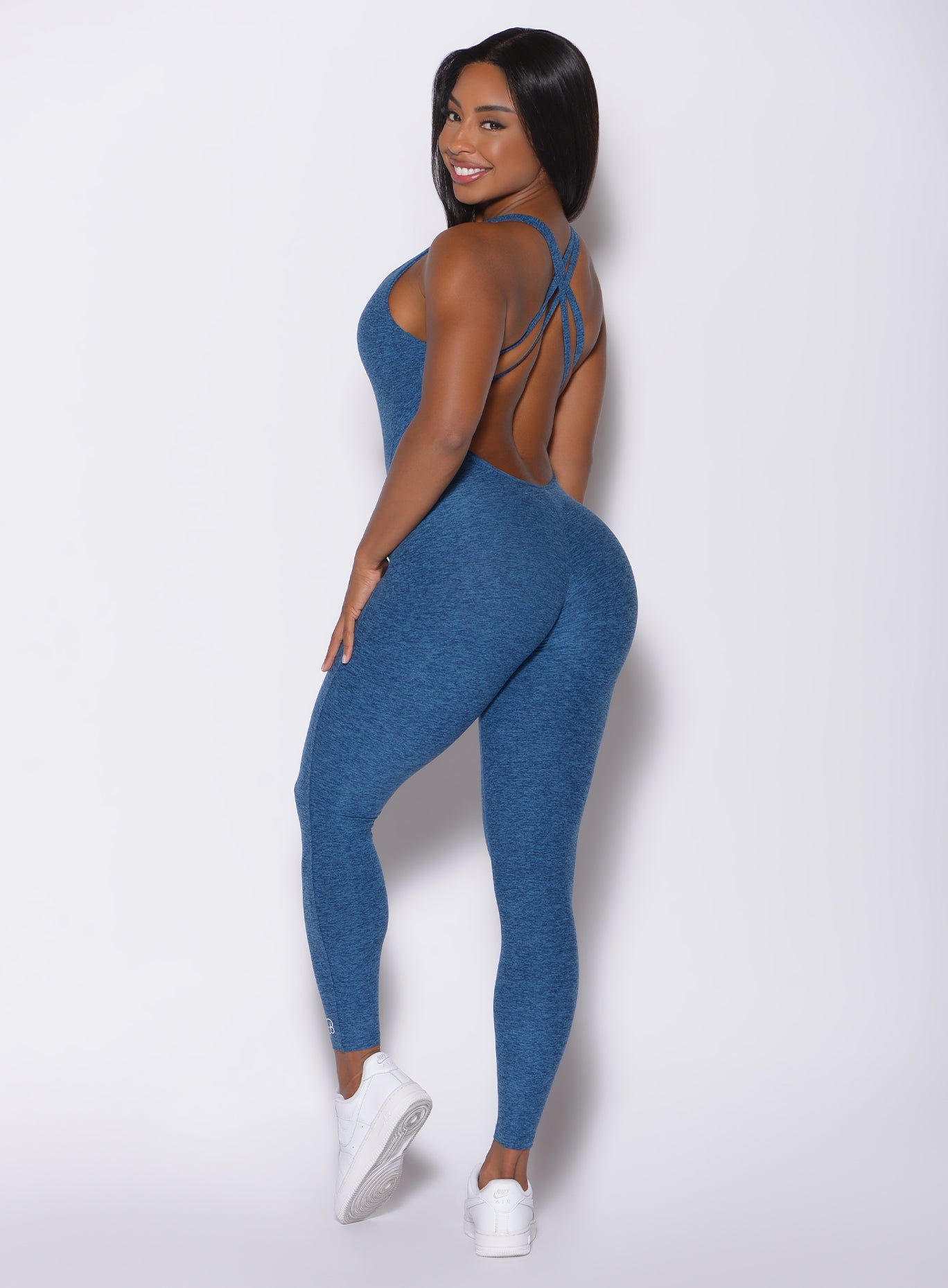 Left side profile view of a model wearing our form bodysuit in ocean color 