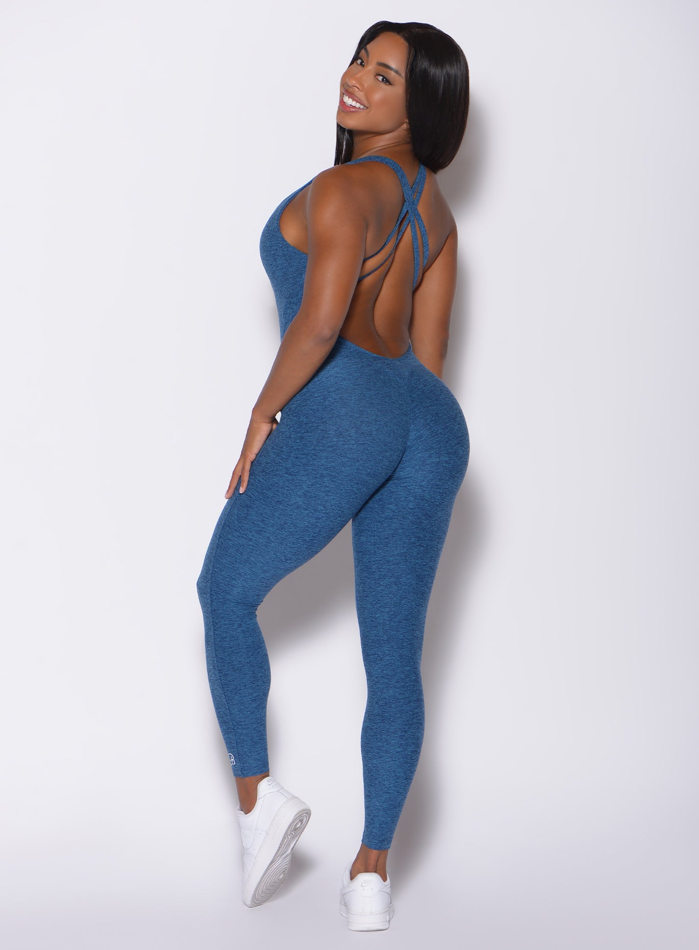 Back profile view of a model angled left wearing our form bodysuit in ocean color 