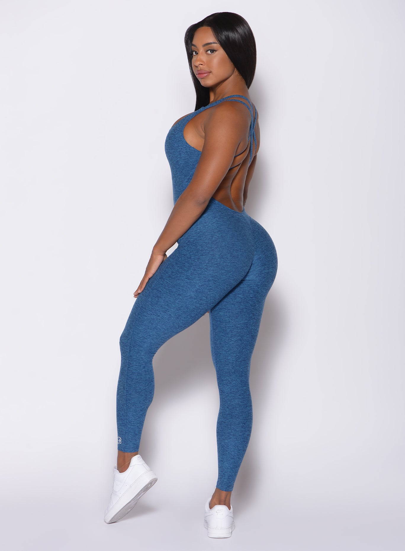 Left side profile view of a model facing to her left wearing our form bodysuit in ocean color