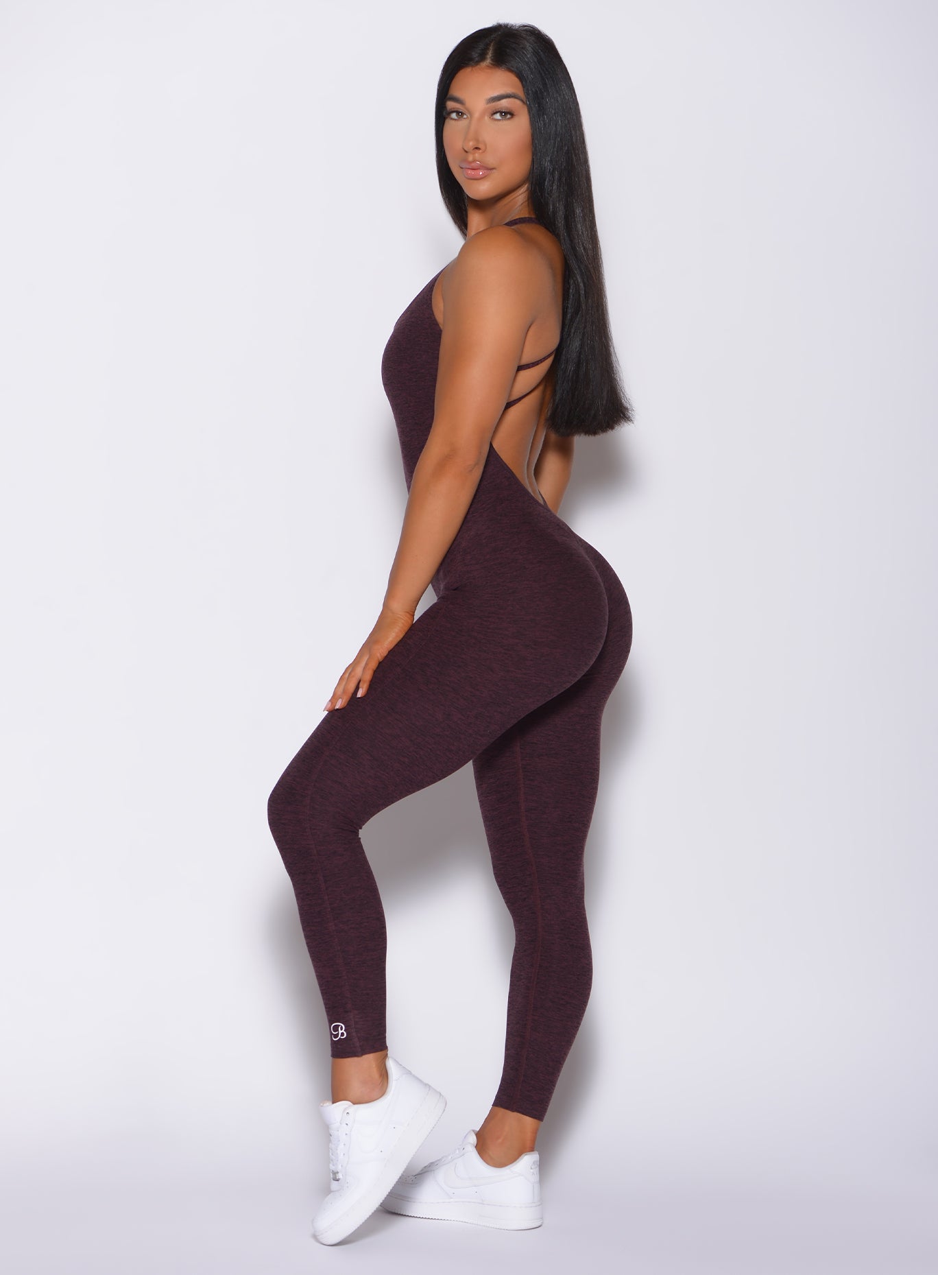 Left side profile view of a model facing to her left wearing our form bodysuit in port color 