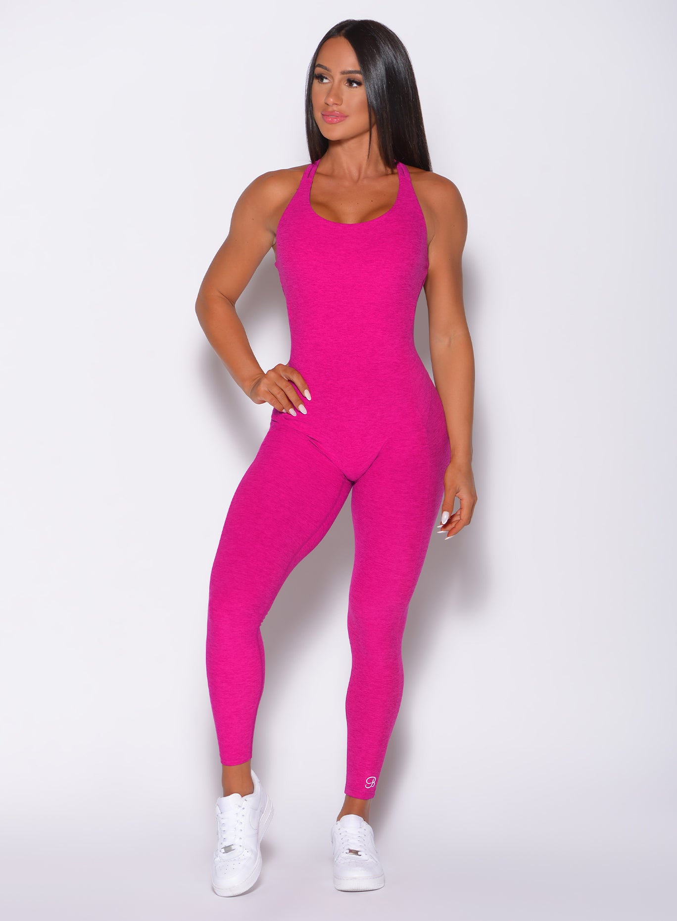 Front profile view of the model with her right hand on waist wearing our form bodysuit in ultra pink 